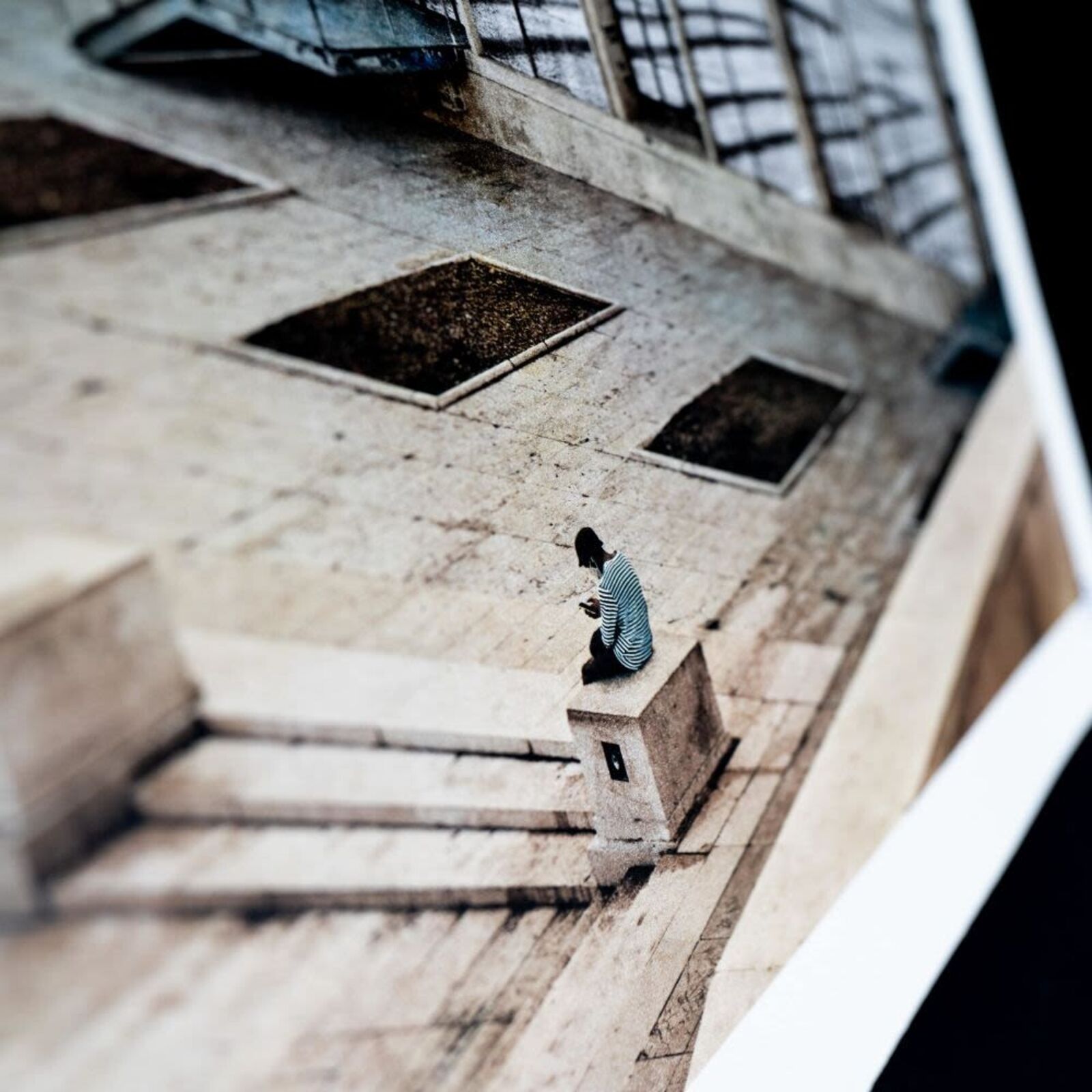 A man sitting on a bench in front of a mural of the Eiffel Tower.