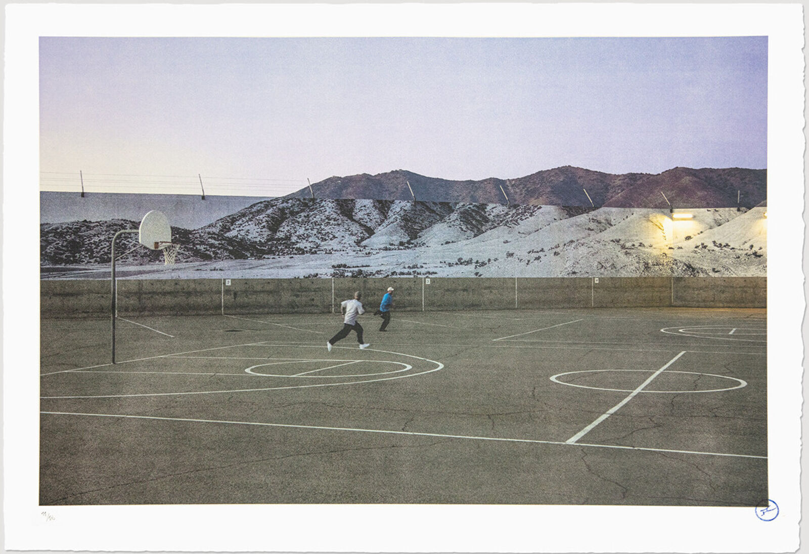 A couple of people playing basketball on a basketball court.