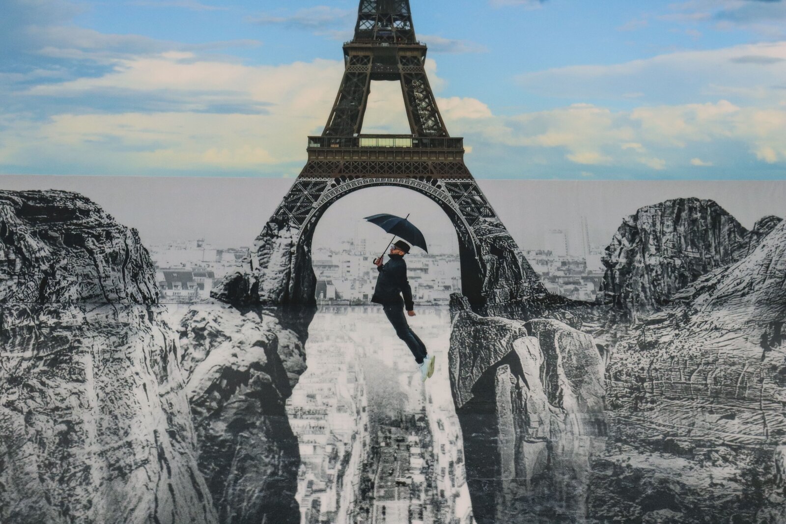 A surreal 3D illusion of a person falling into a deep pit beneath the Eiffel Tower.