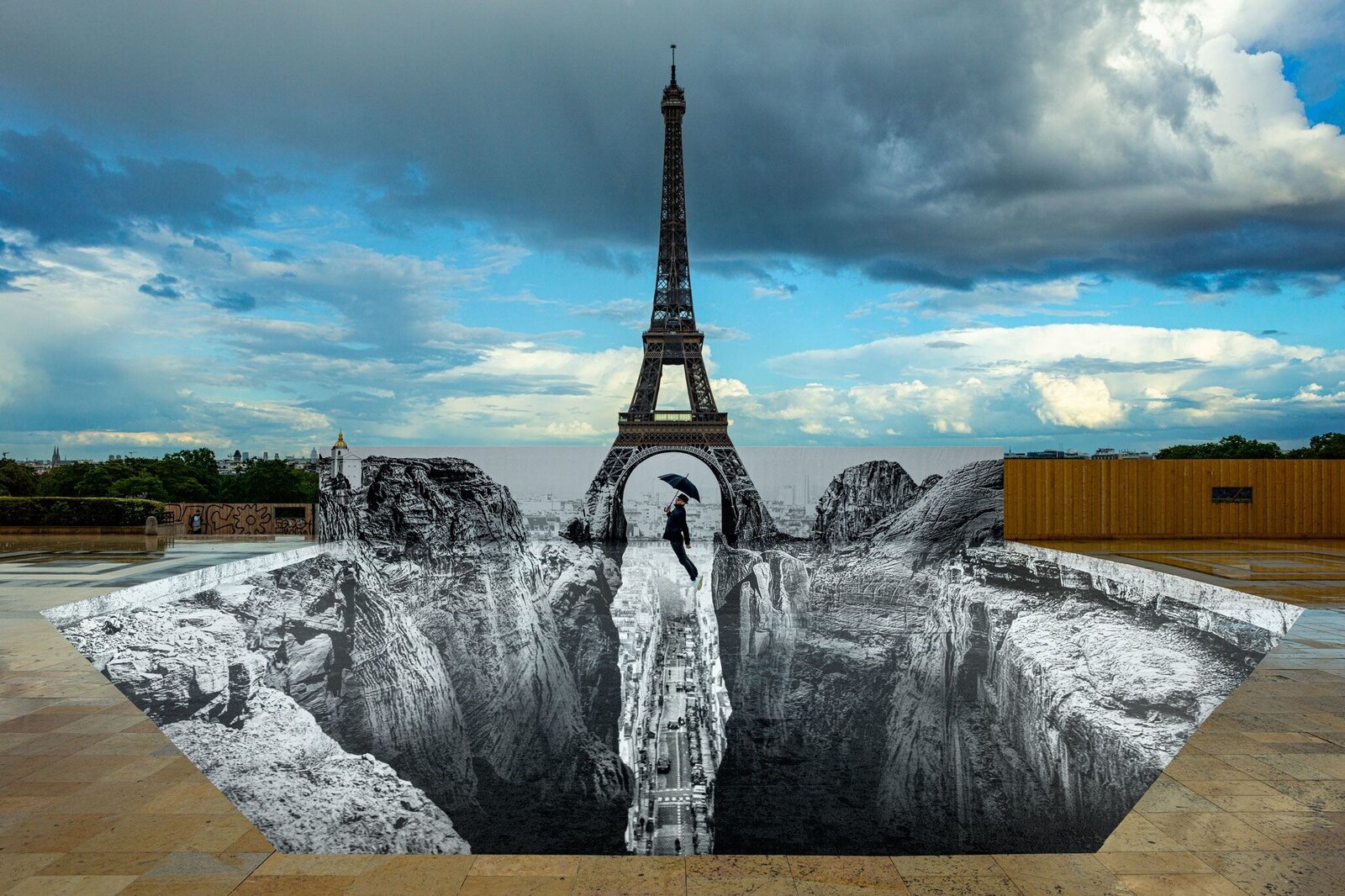 A surreal 3D illusion of a person falling into a deep pit beneath the Eiffel Tower.