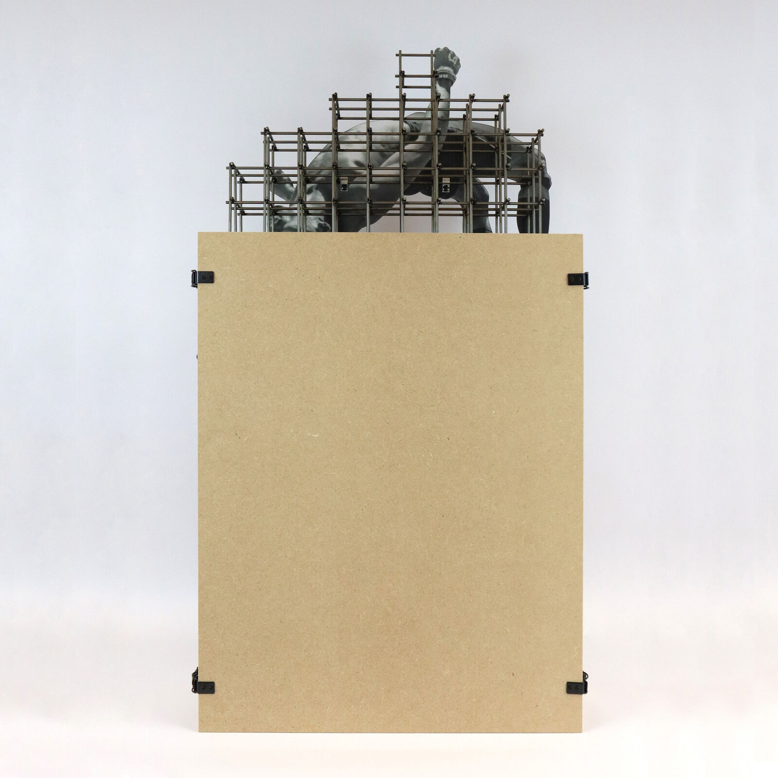 A miniature architectural model of a high-rise building topped by a suspended, contorted human figure.