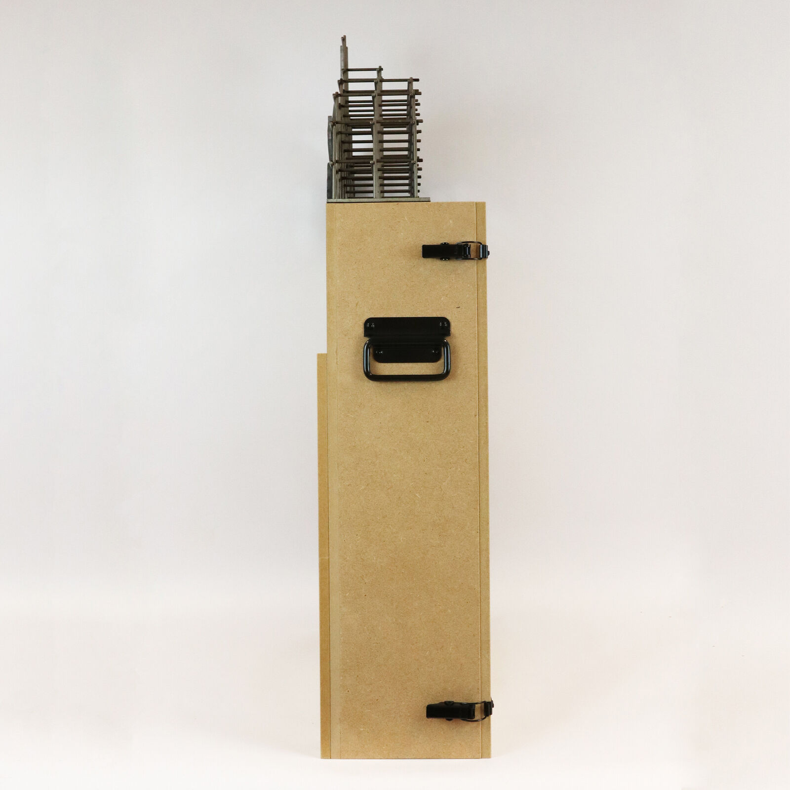 A miniature architectural model of a high-rise building topped by a suspended, contorted human figure.