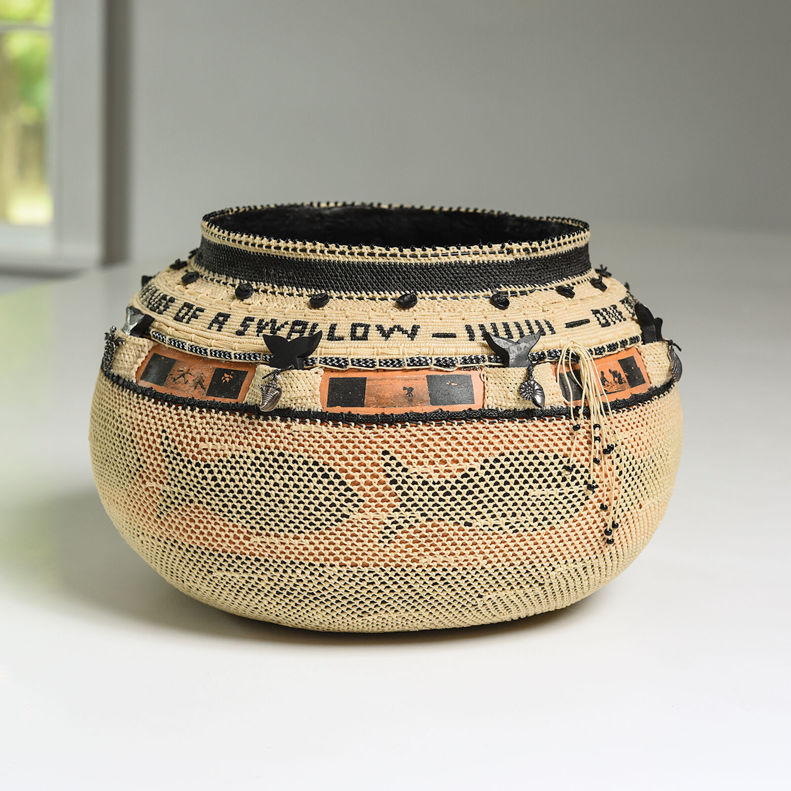 A woven basket with intricate black and orange decorative bands.