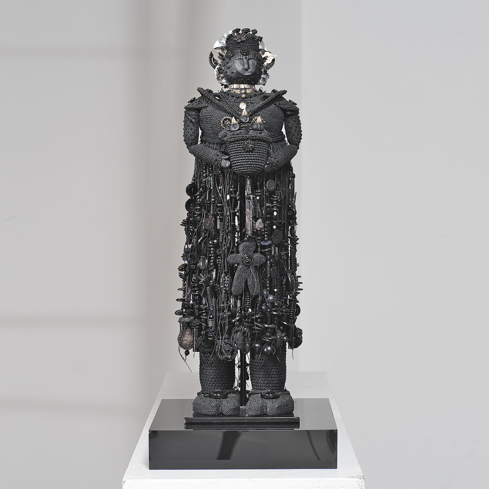 A sculpture of a woman in a black dress on a white pedestal.