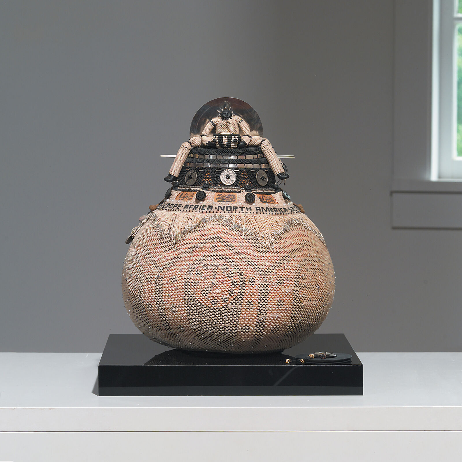 A sculpture of a man sitting on top of a large vase.