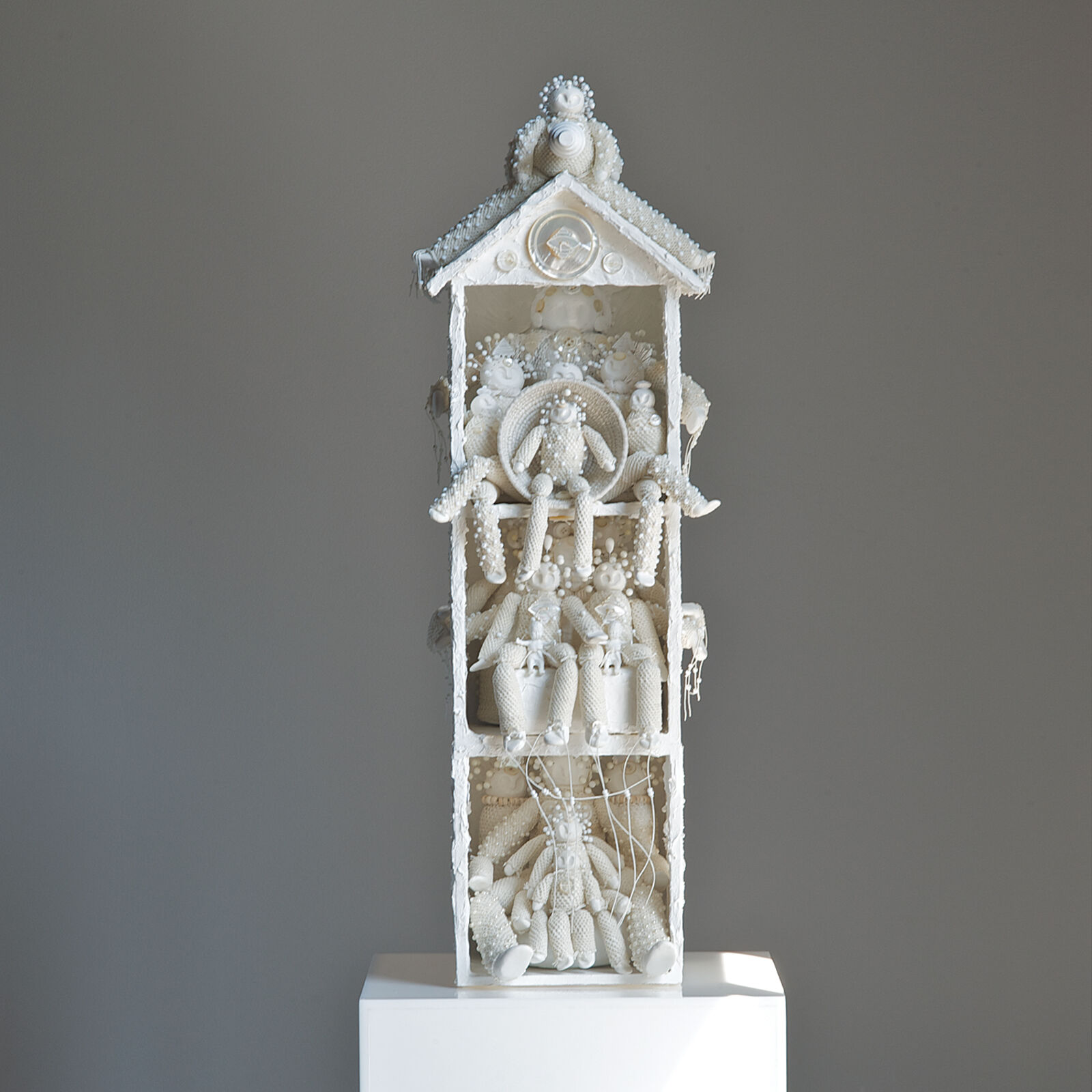 A white sculptural tower filled with intricate figures and textures.