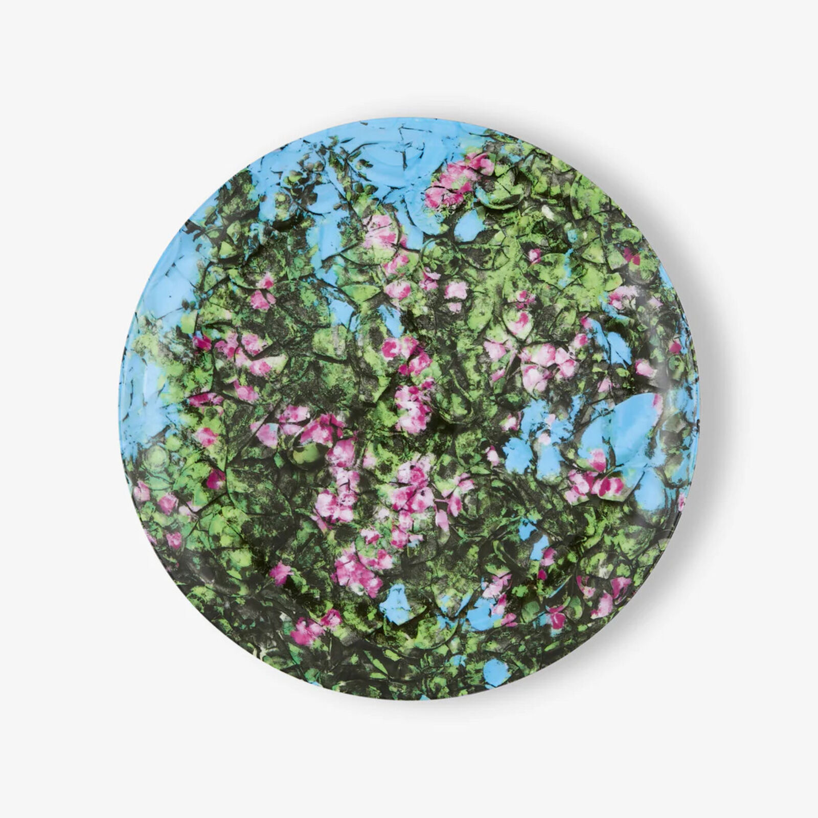 A round plate with pink flowers on a blue background.