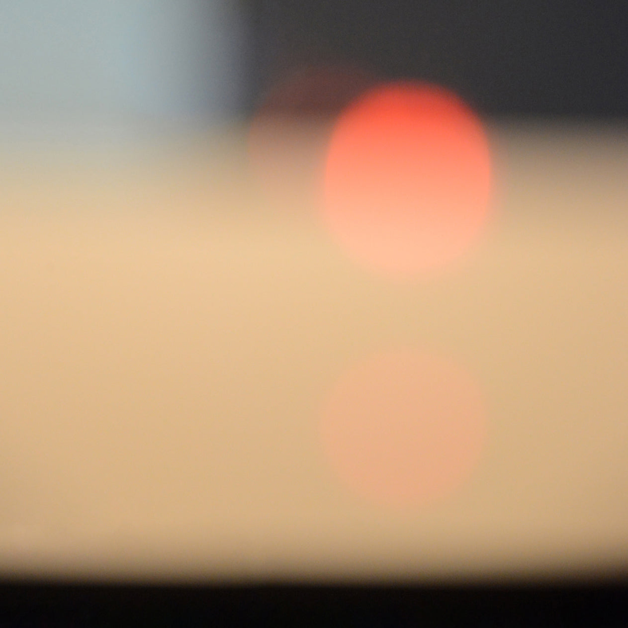 A blurry image of the sun setting over the ocean.