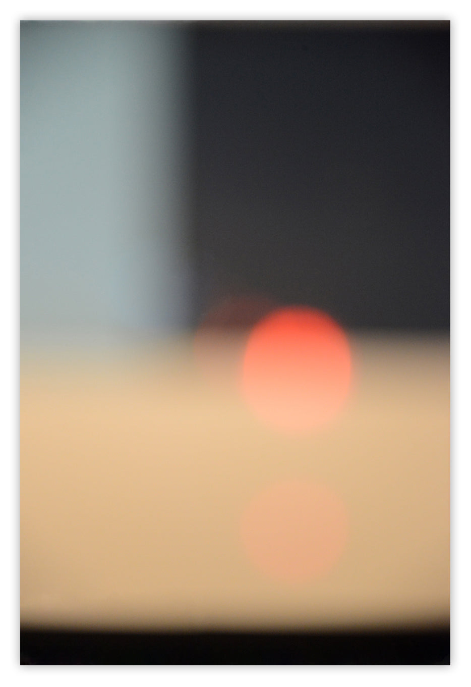 A blurry image of the sun setting over the ocean.