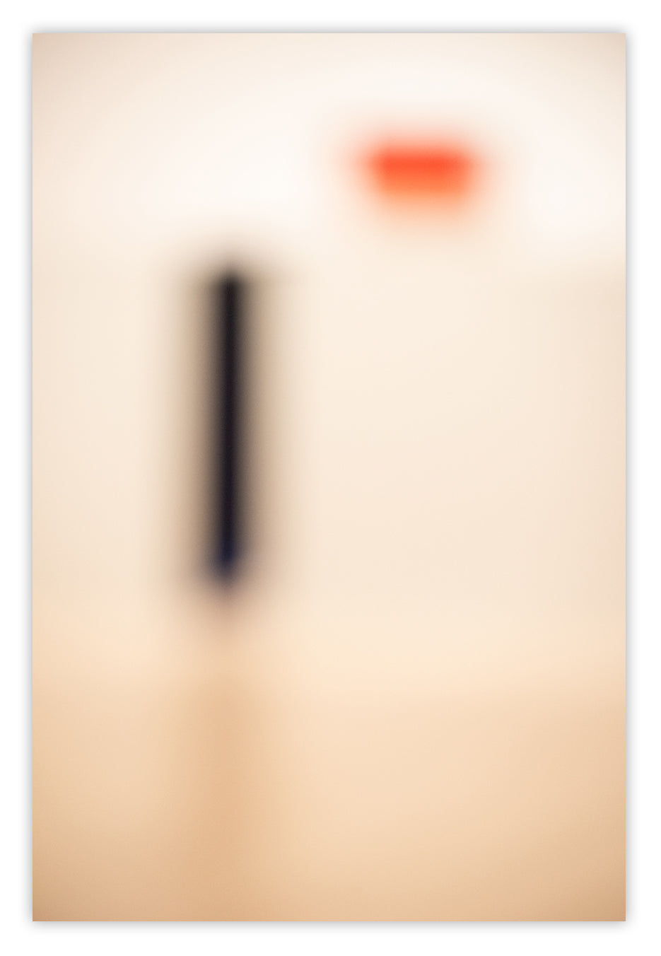 A blurry image of a red dot in the middle of a white wall.