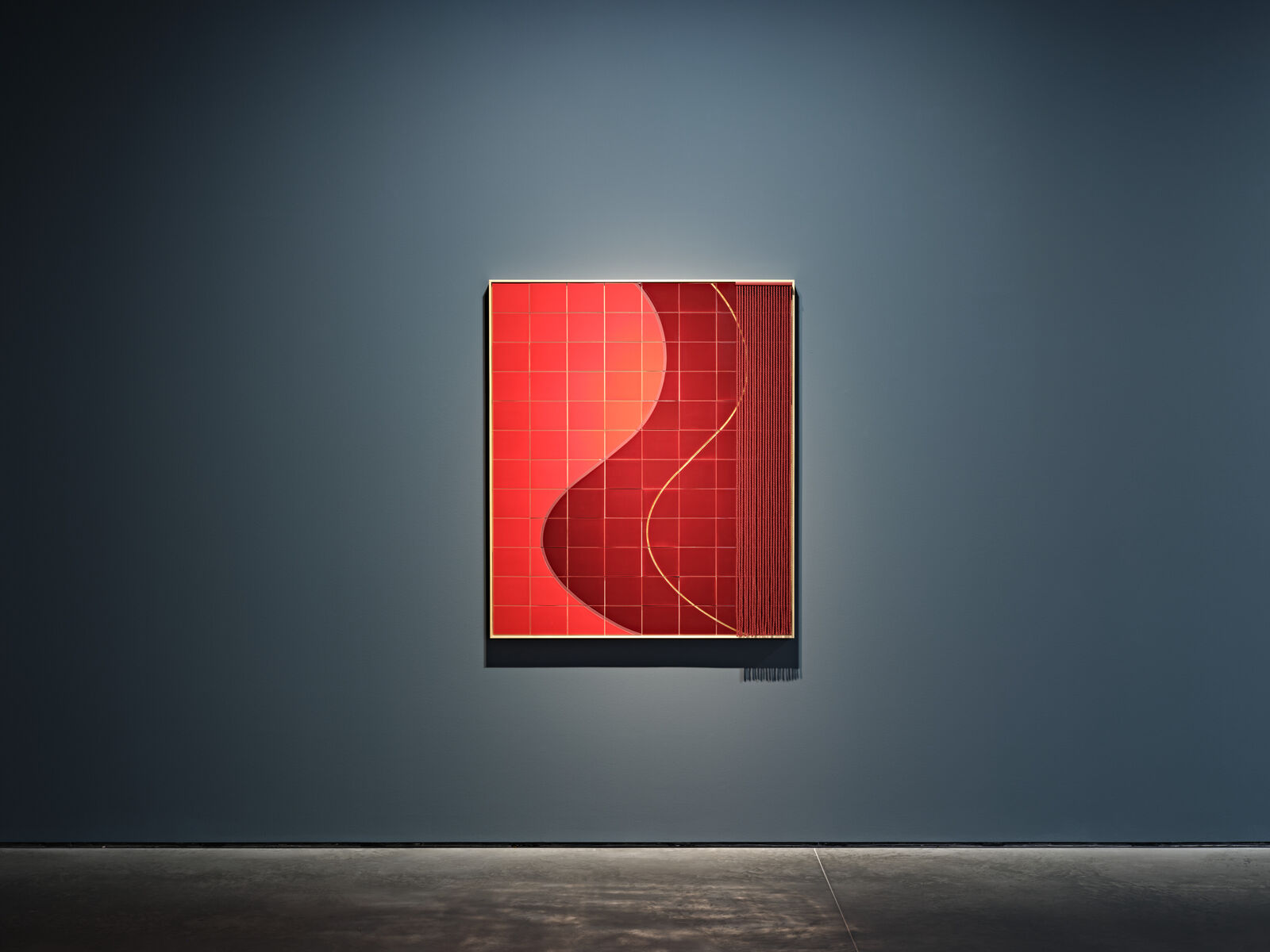 A red and black painting on a wall in a dark room.