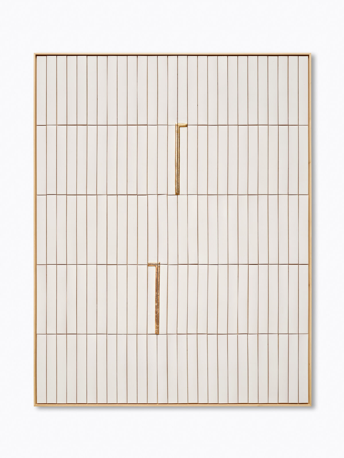 A white and gold wall hanging on a white wall.