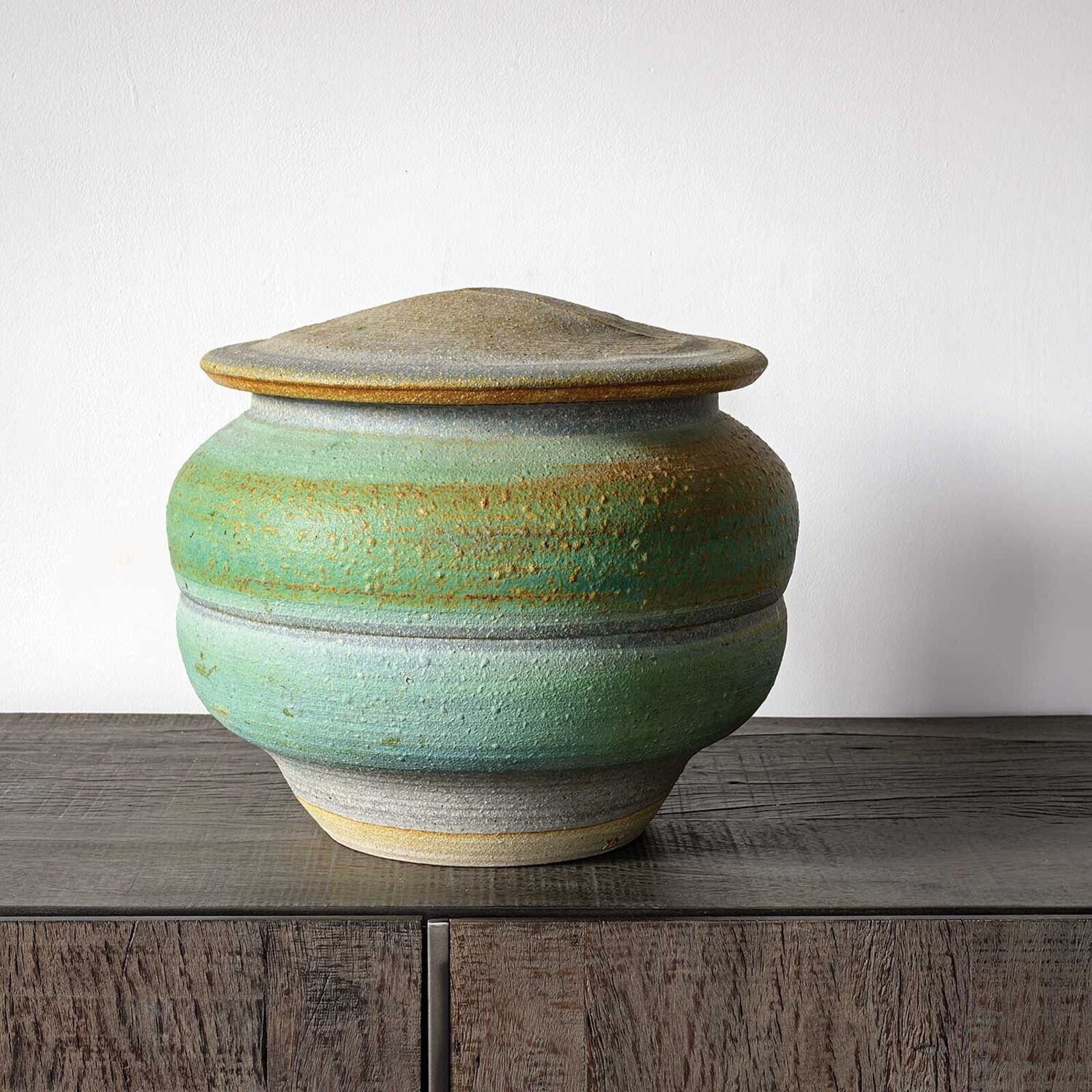 A green and yellow vase sitting on top of a wooden table.