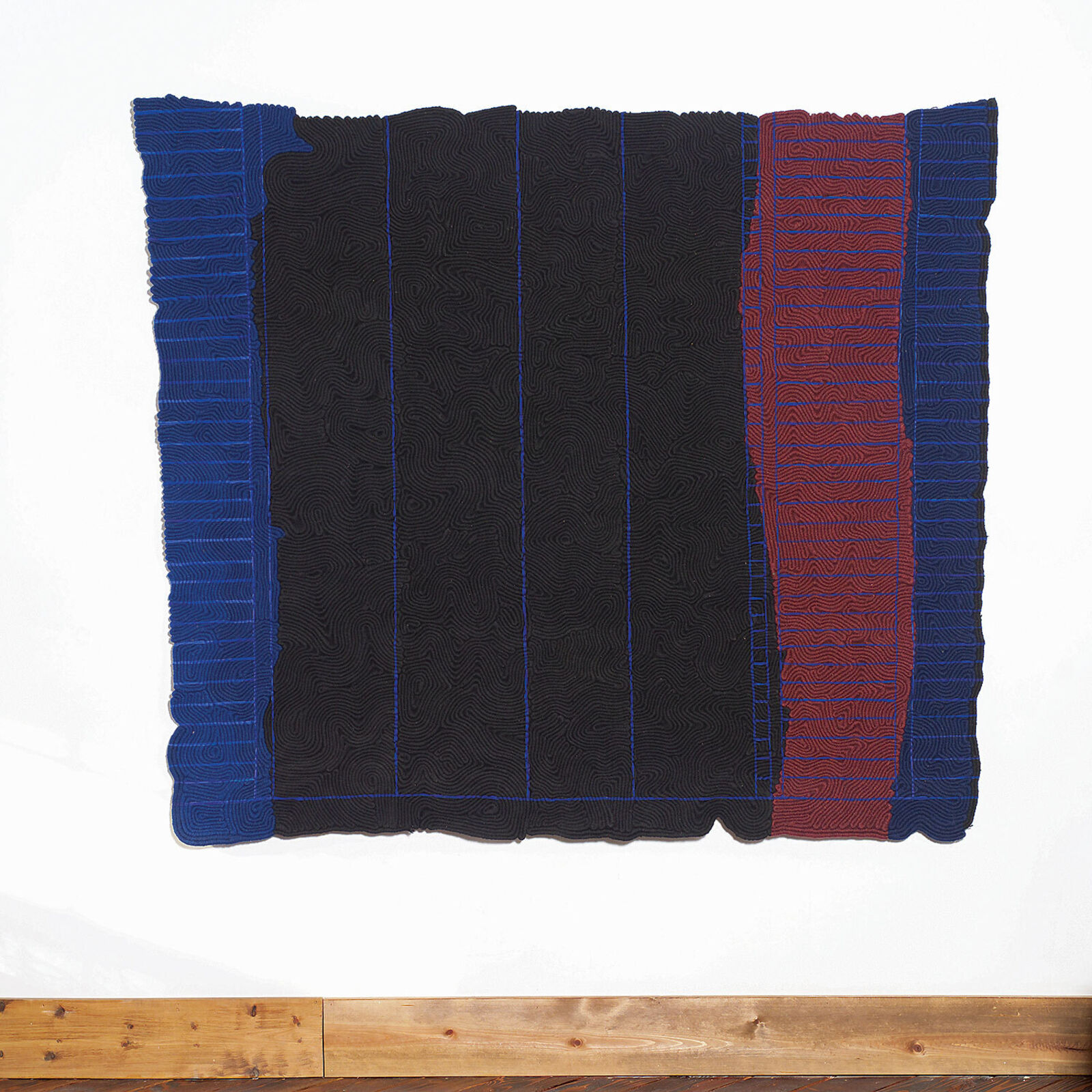 A black and blue blanket hanging on a wall in a room.