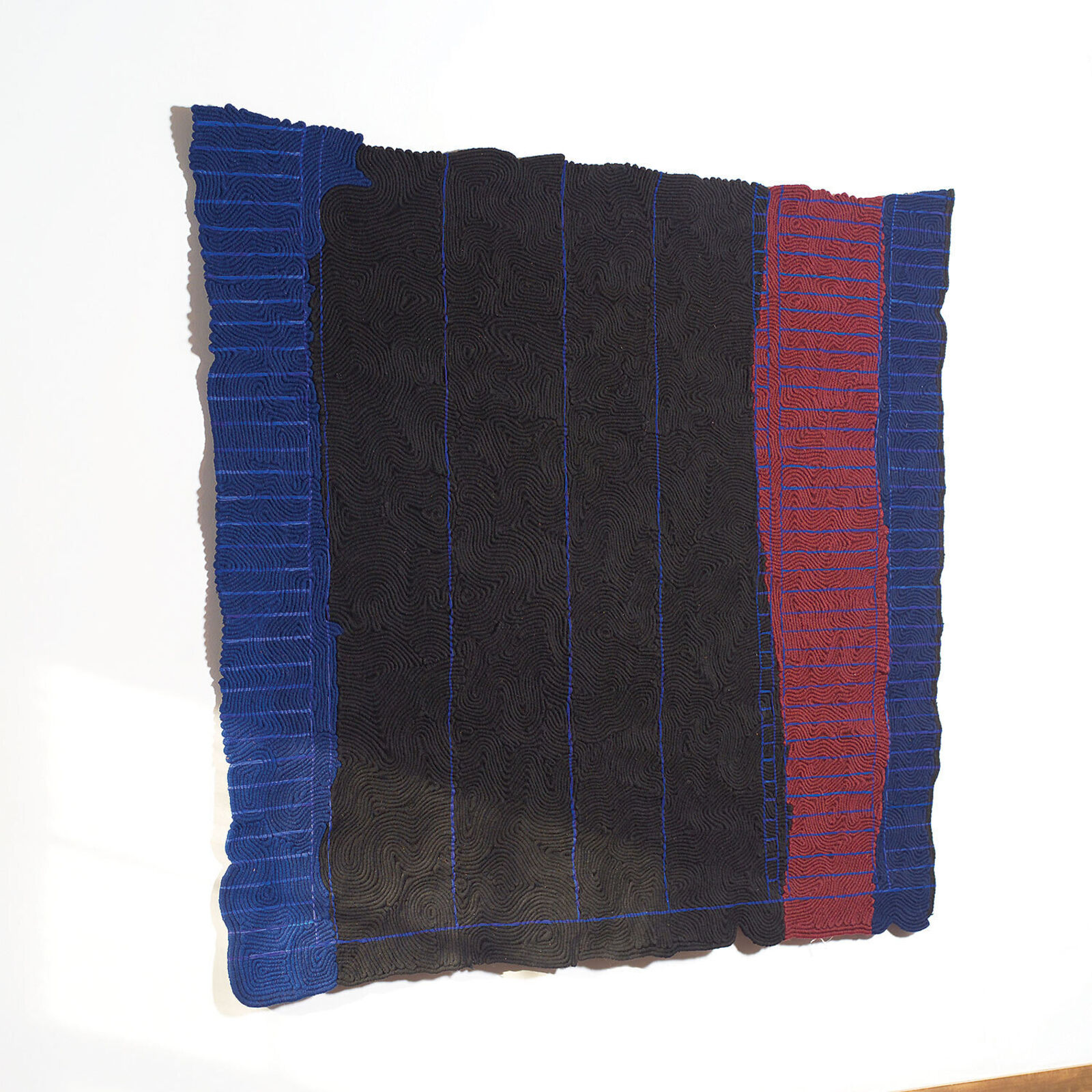 A black and blue blanket hanging on a wall in a room.