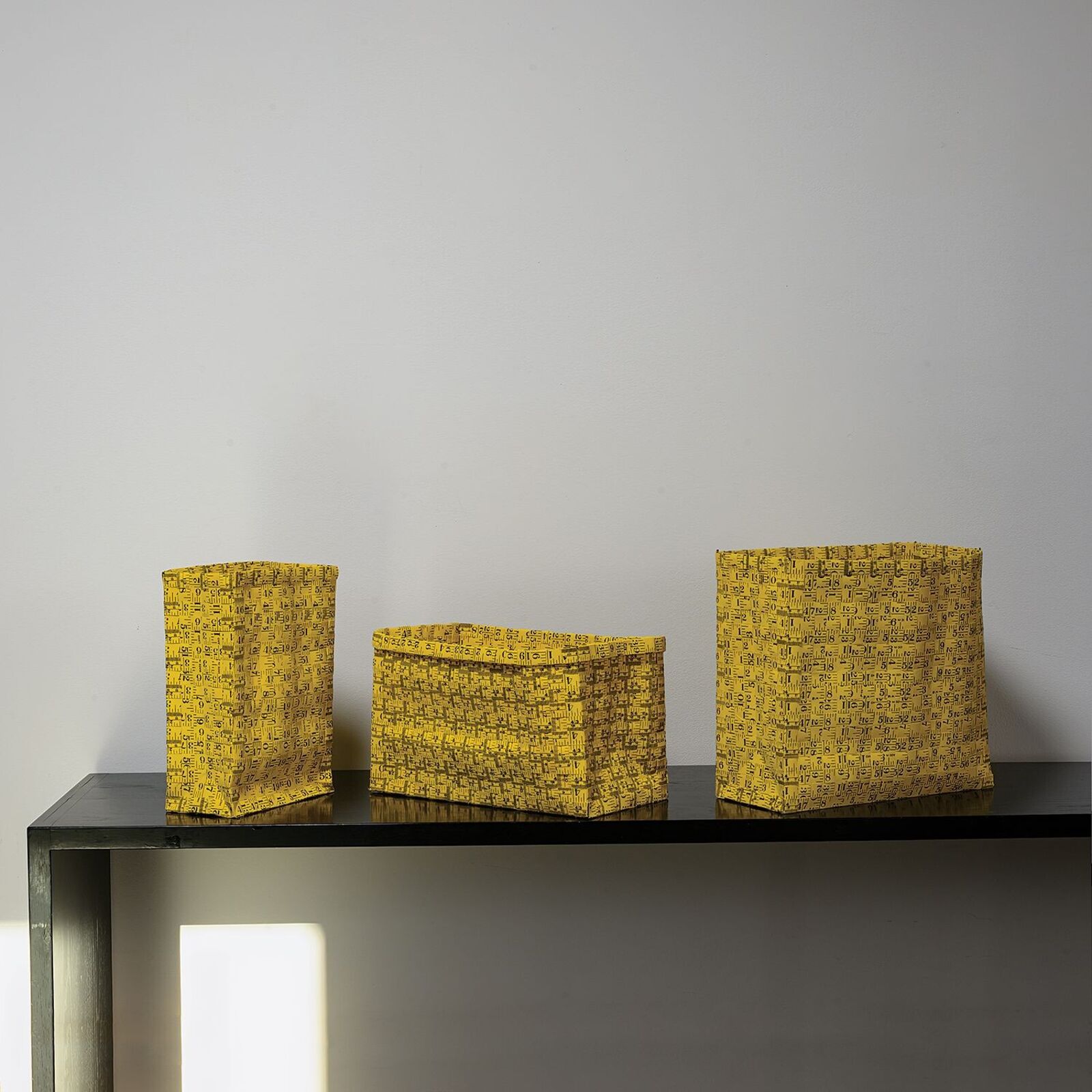 A yellow gift bag with a black geometric pattern sits on a dark table.
