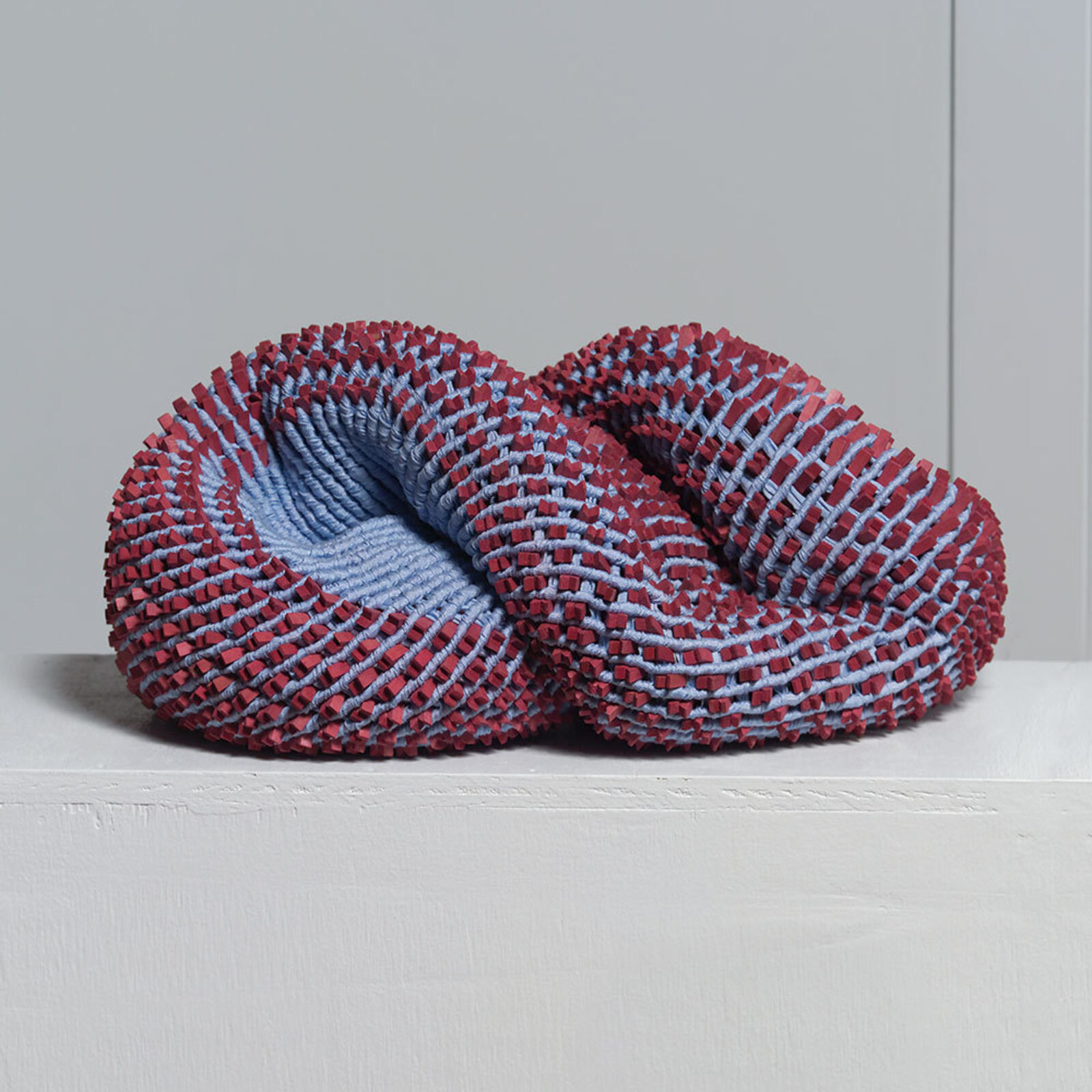 A red and blue knitted object on a white surface.