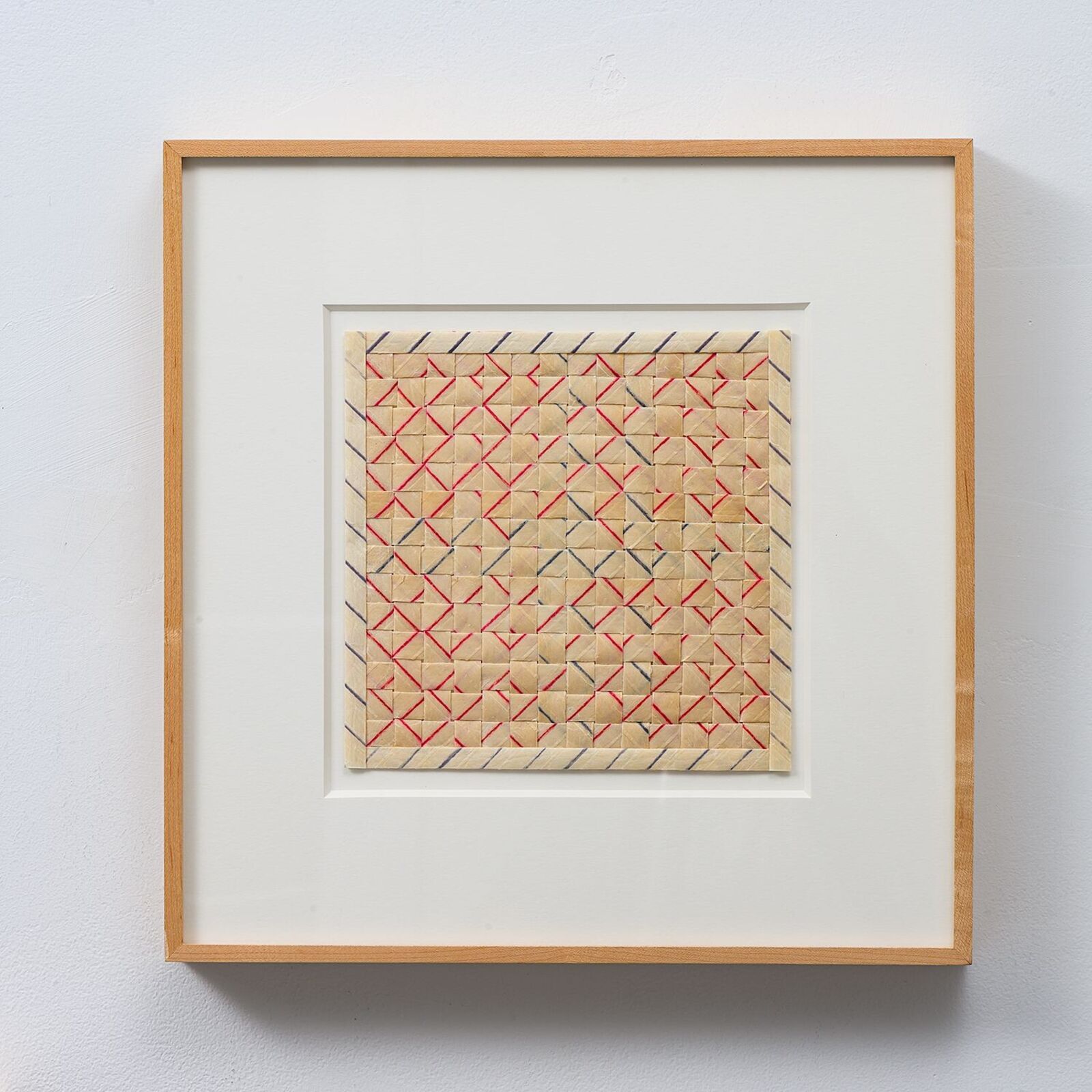 A framed textile artwork featuring a geometric grid pattern with red and black threads on a beige background.