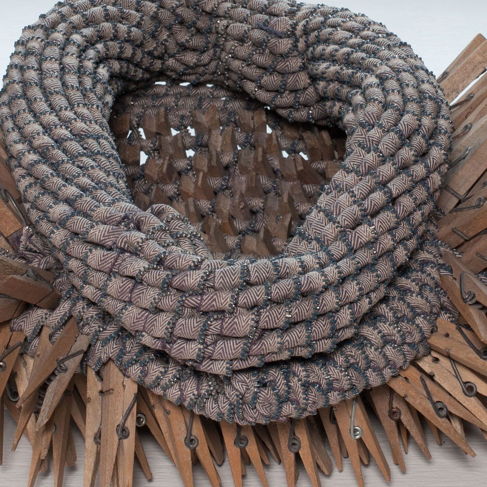 A necklace made out of clothes pins on a window sill.