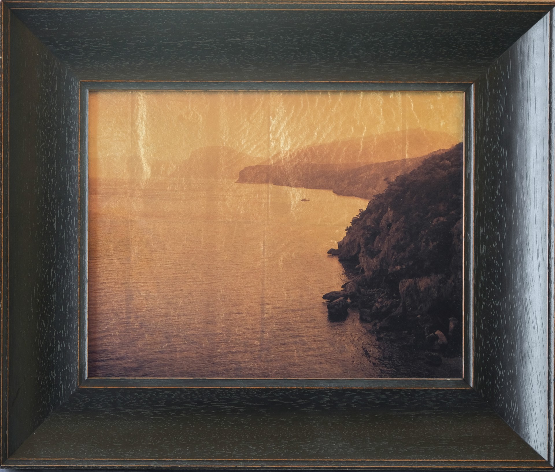 A picture of a view of the ocean in a wooden frame.
