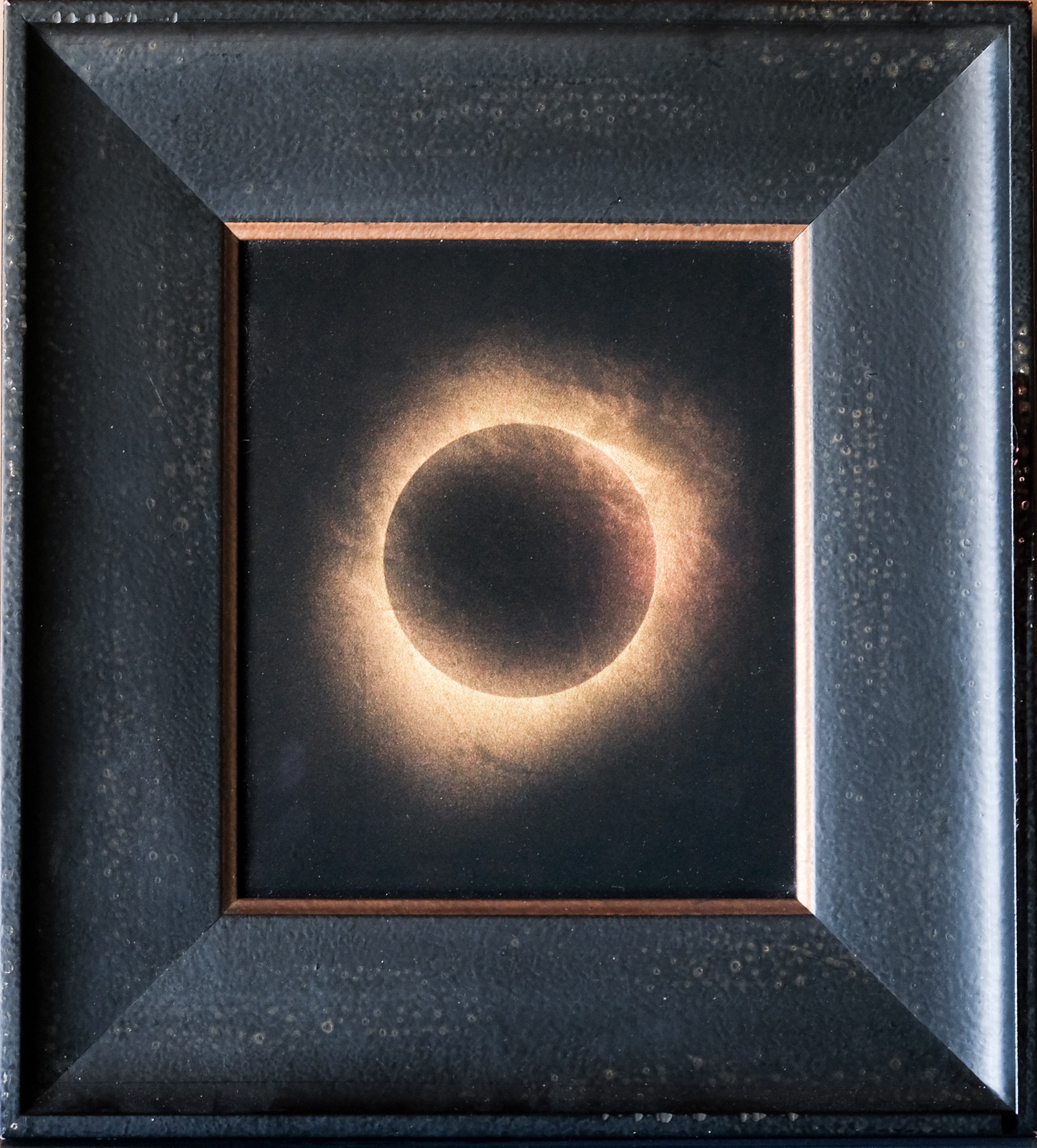 A picture of a solar eclipse in a black frame.