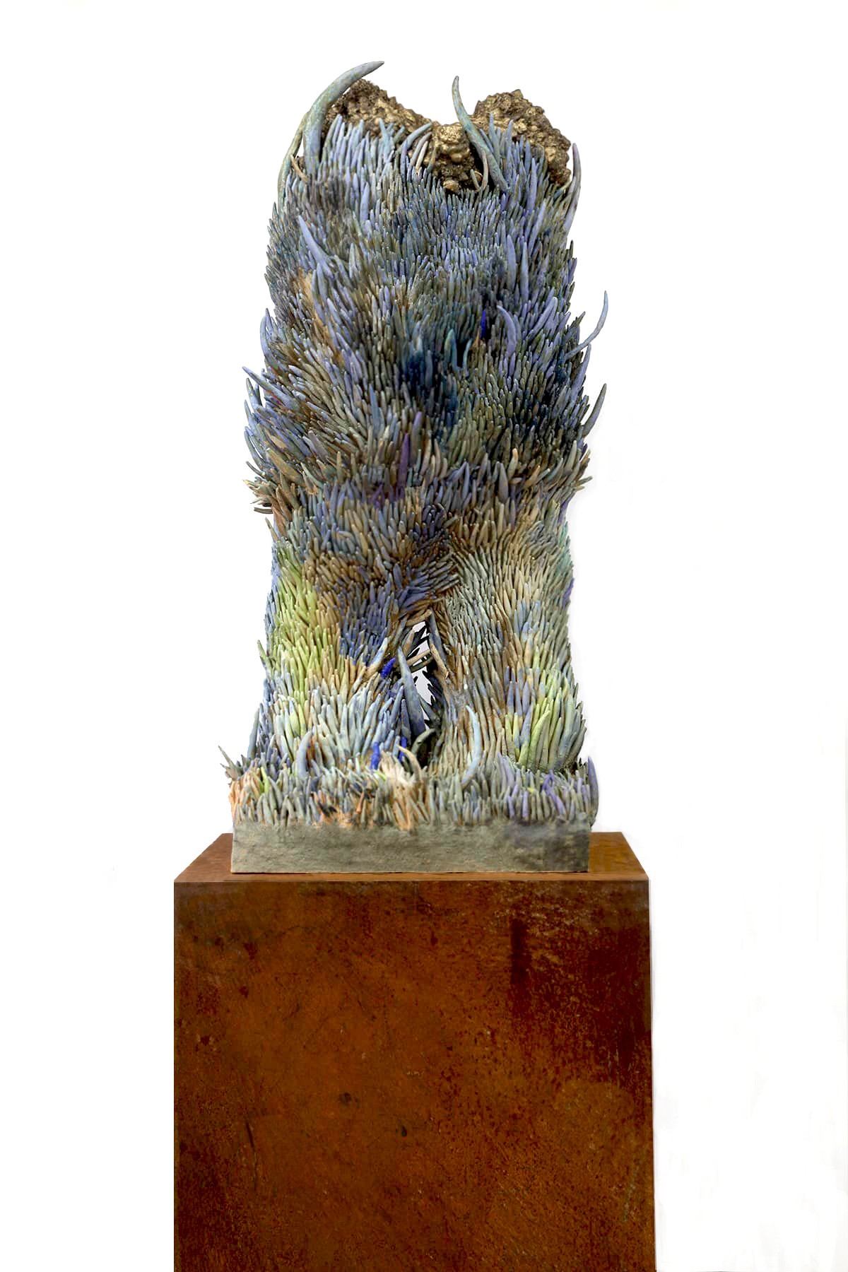 A sculpture of a bird sitting on top of a metal pedestal in the grass.