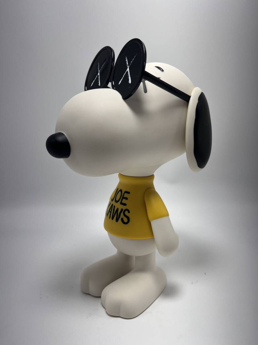 A stylized white dog figure wearing oversized sunglasses and a yellow shirt with black text.