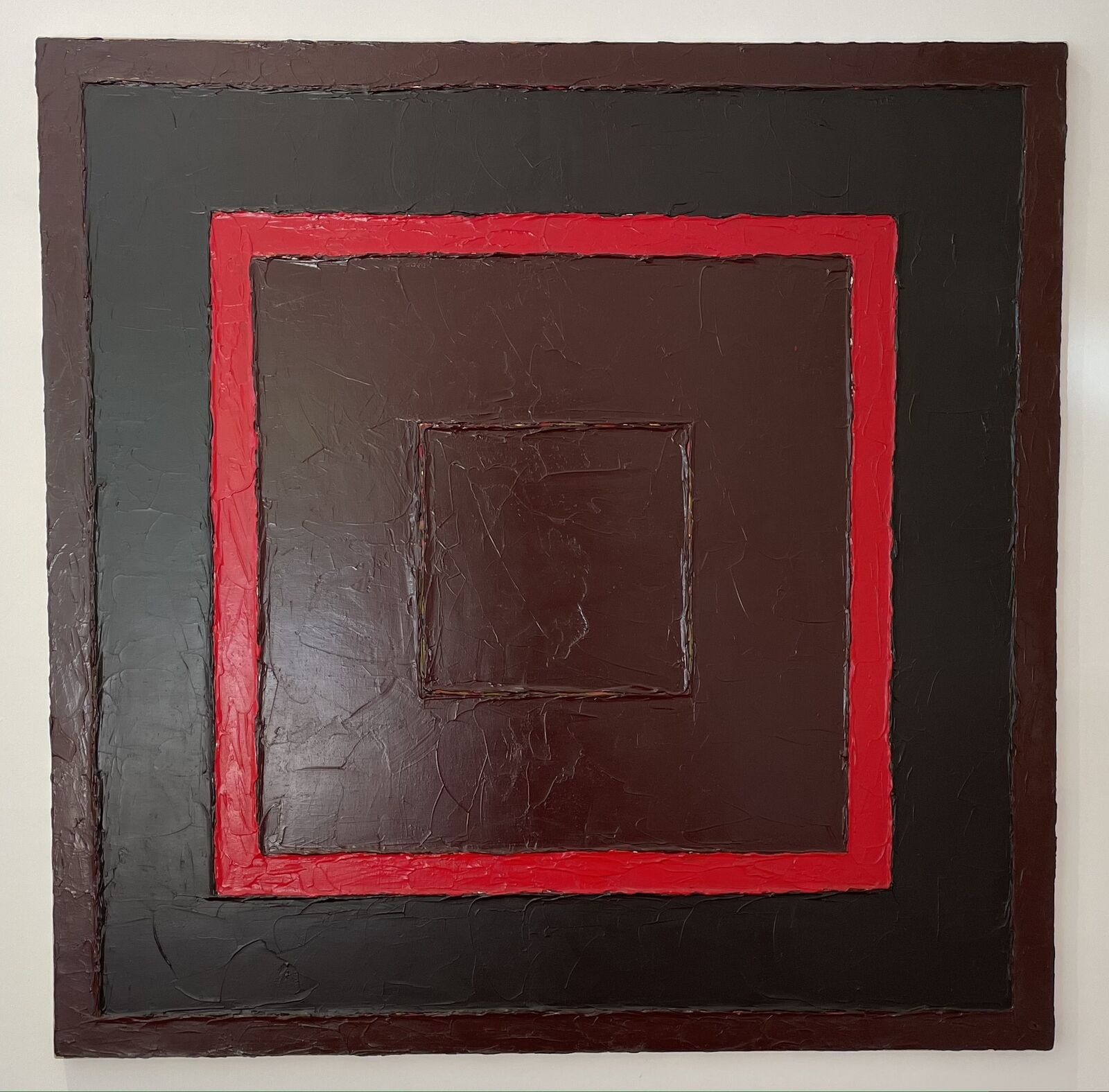 A painting on a wall with a red square in the middle.