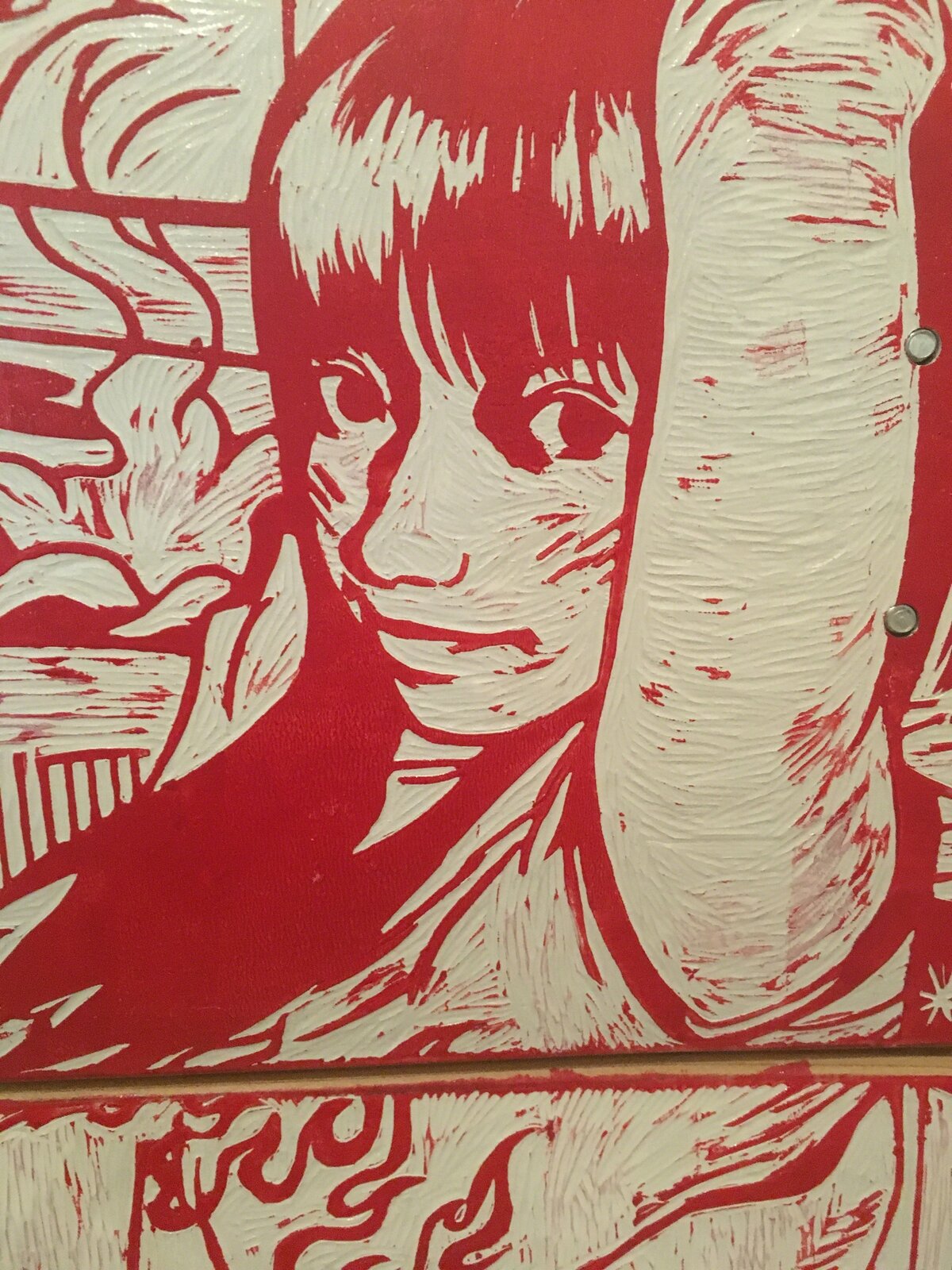 A red and white graphic print on three stacked skateboard decks displayed on a wooden stand.