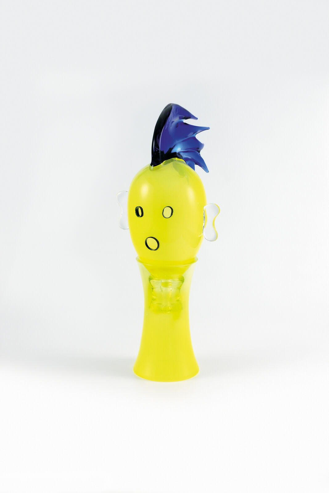 A yellow vase with a blue mohawk on top of it.