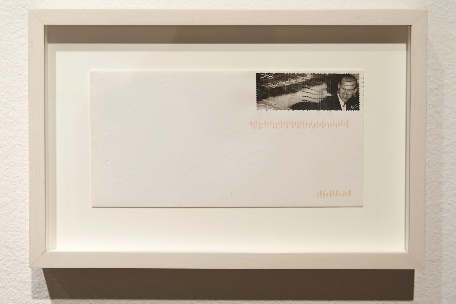 A minimalist white envelope with a black-and-white portrait stamp and orange barcode-like markings.