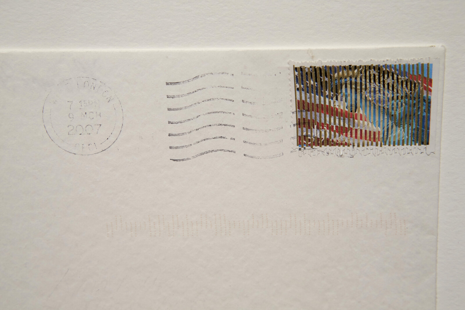 A minimalist white envelope with a colorful postage stamp and faint red markings.