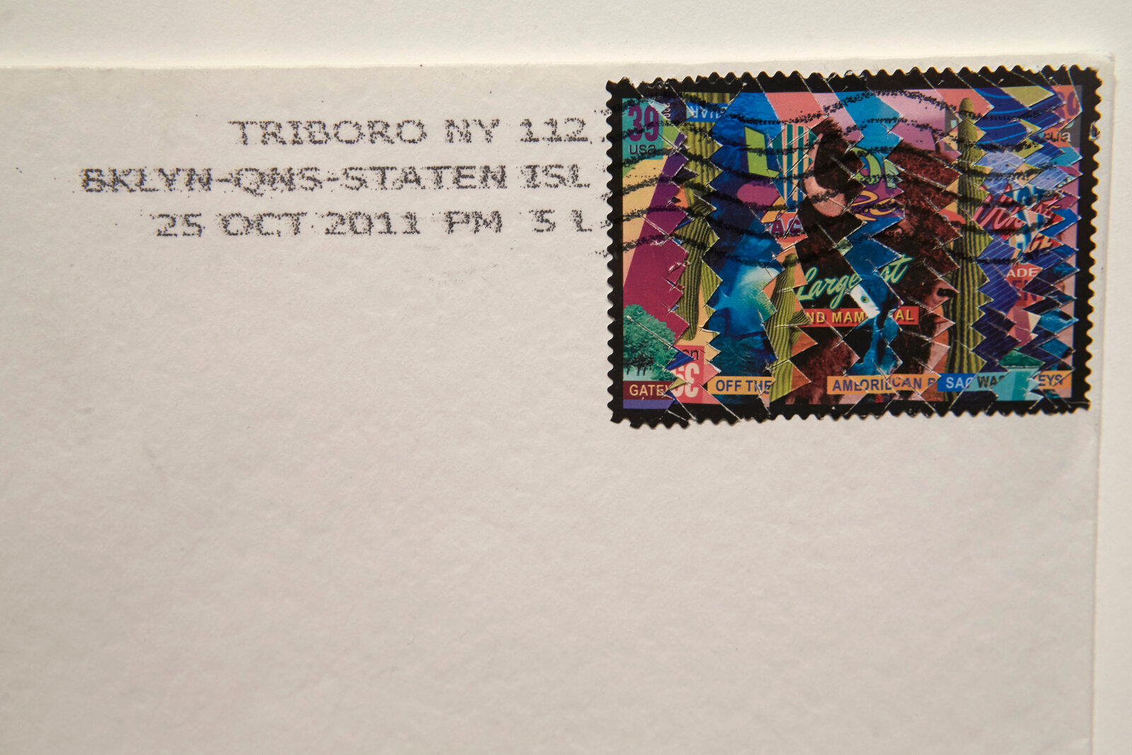 A white envelope with a colorful geometric stamp and postal markings.