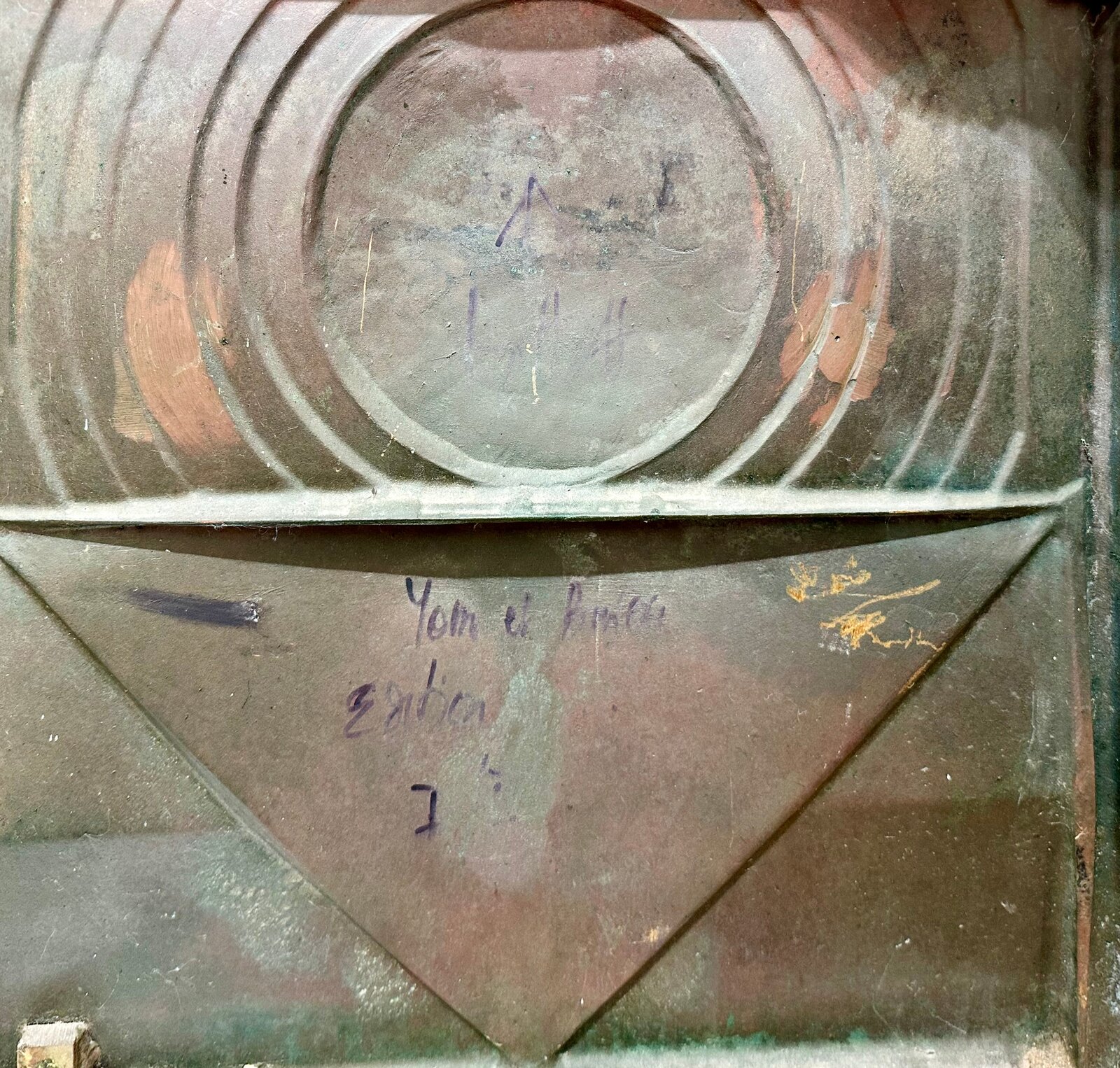 A square relief sculpture featuring a central sphere and geometric triangles with a dark, patinated metal surface.