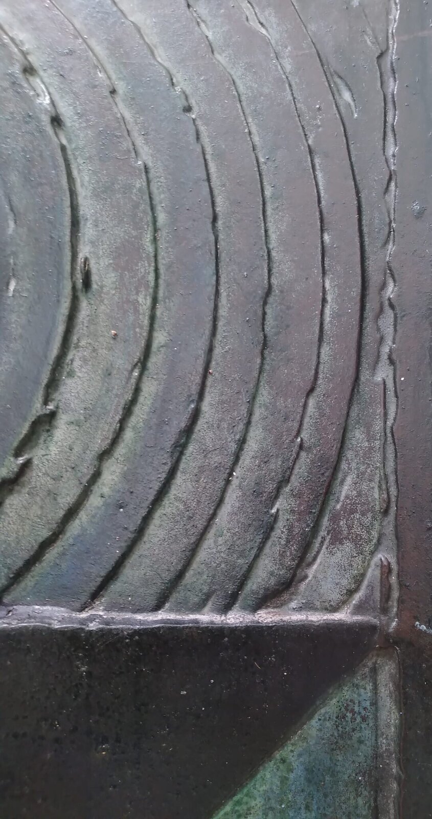 A square relief sculpture featuring a central sphere and geometric triangles with a dark, patinated metal surface.