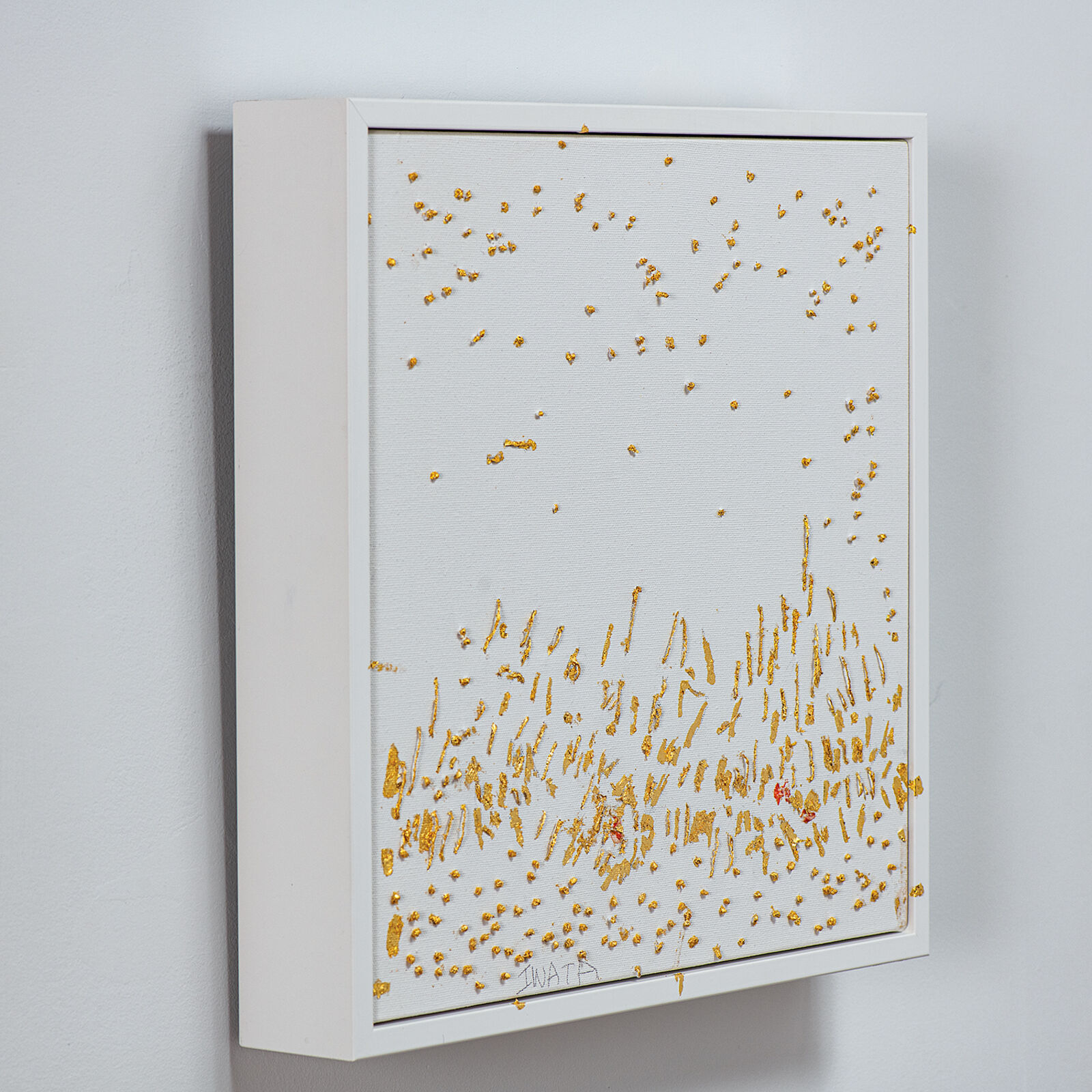 A textured canvas artwork featuring scattered gold leaf fragments and a dense cluster of vertical strokes at the bottom.