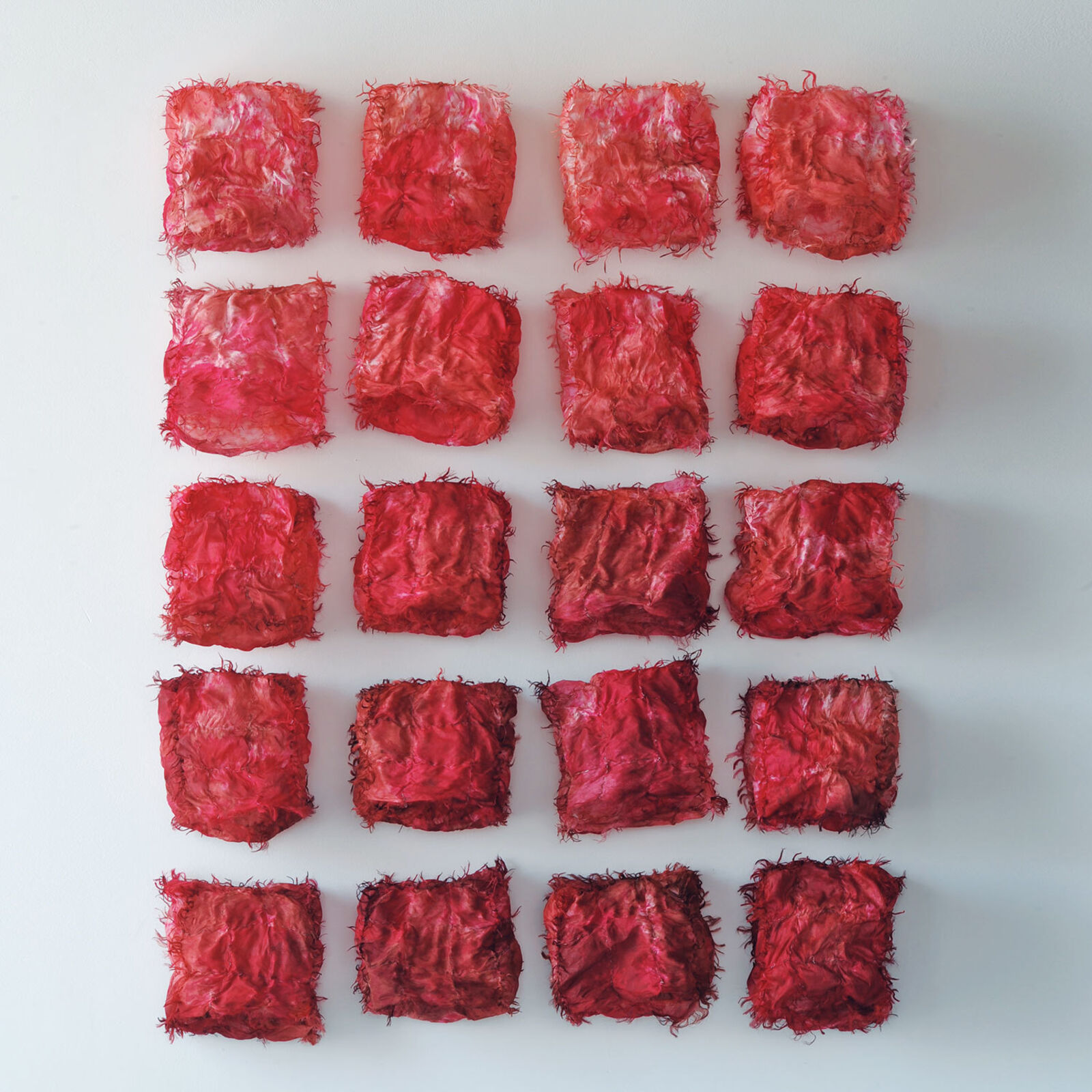 A grid of twenty red, crumpled fabric squares arranged in a neat pattern against a plain background.