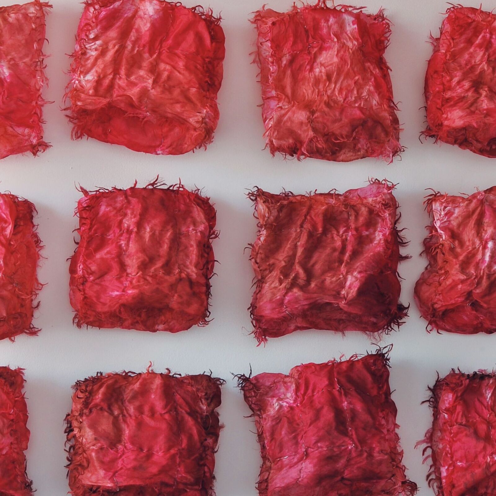 A grid of twenty red, crumpled fabric squares arranged in a neat pattern against a plain background.