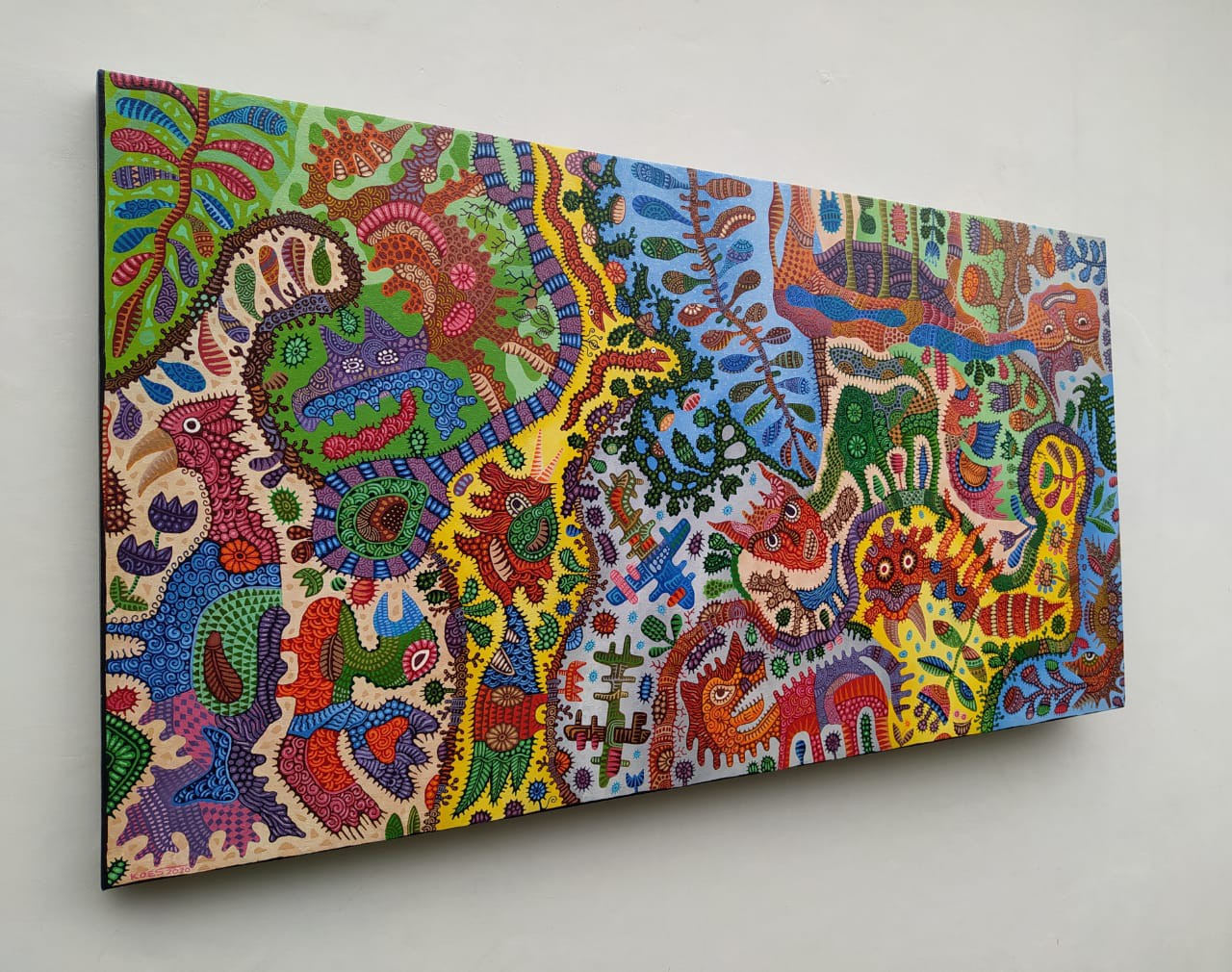 A colorful painting on a white wall in a room.