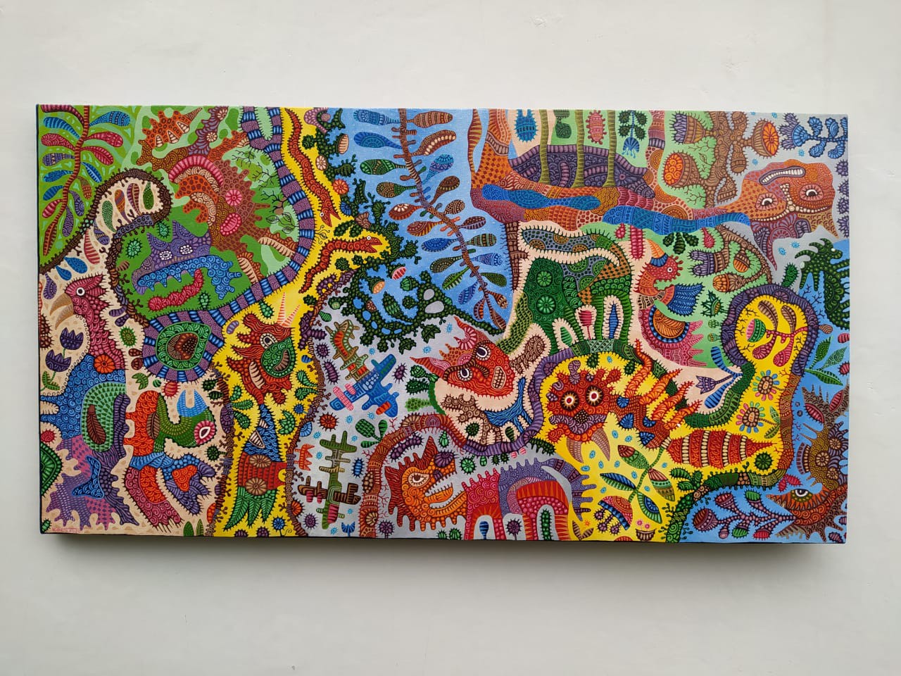 A colorful painting on a white wall in a room.