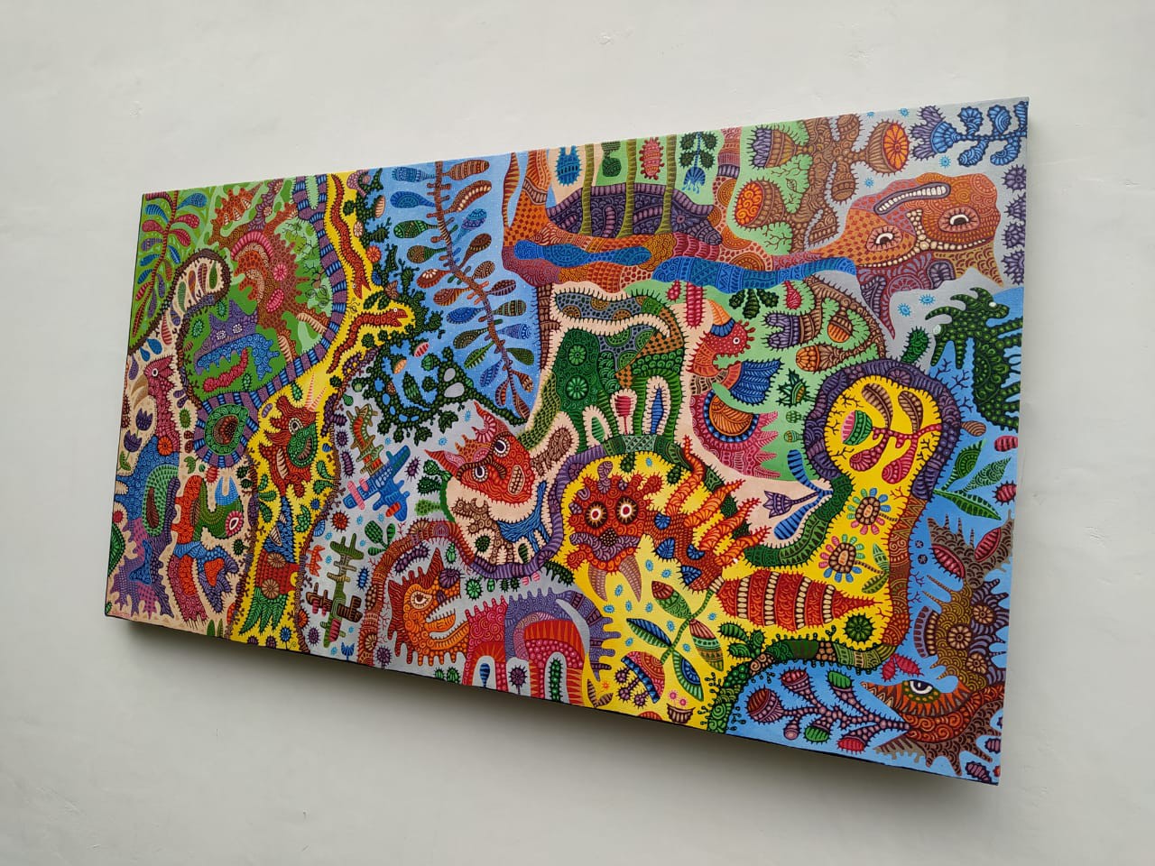 A colorful painting on a white wall in a room.
