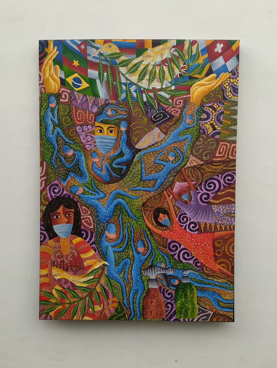 A vibrant, patterned painting of a central tree-like figure with multiple faces and figures, surrounded by flags and nature elements.