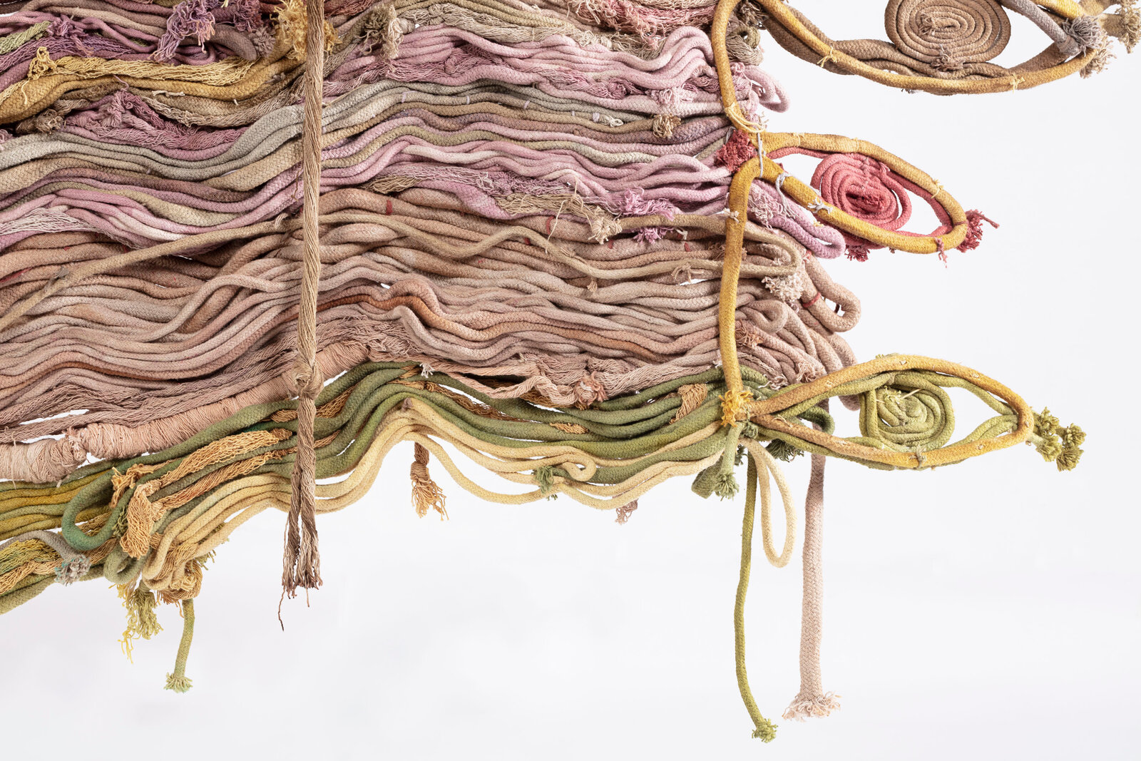 A textured textile artwork featuring layered, wavy threads in earthy tones.
