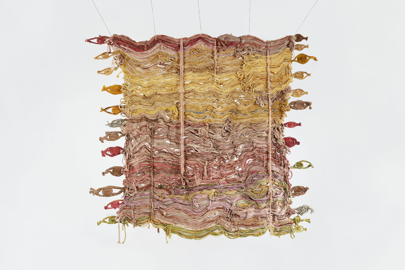 A textured textile artwork featuring layered, wavy threads in earthy tones.