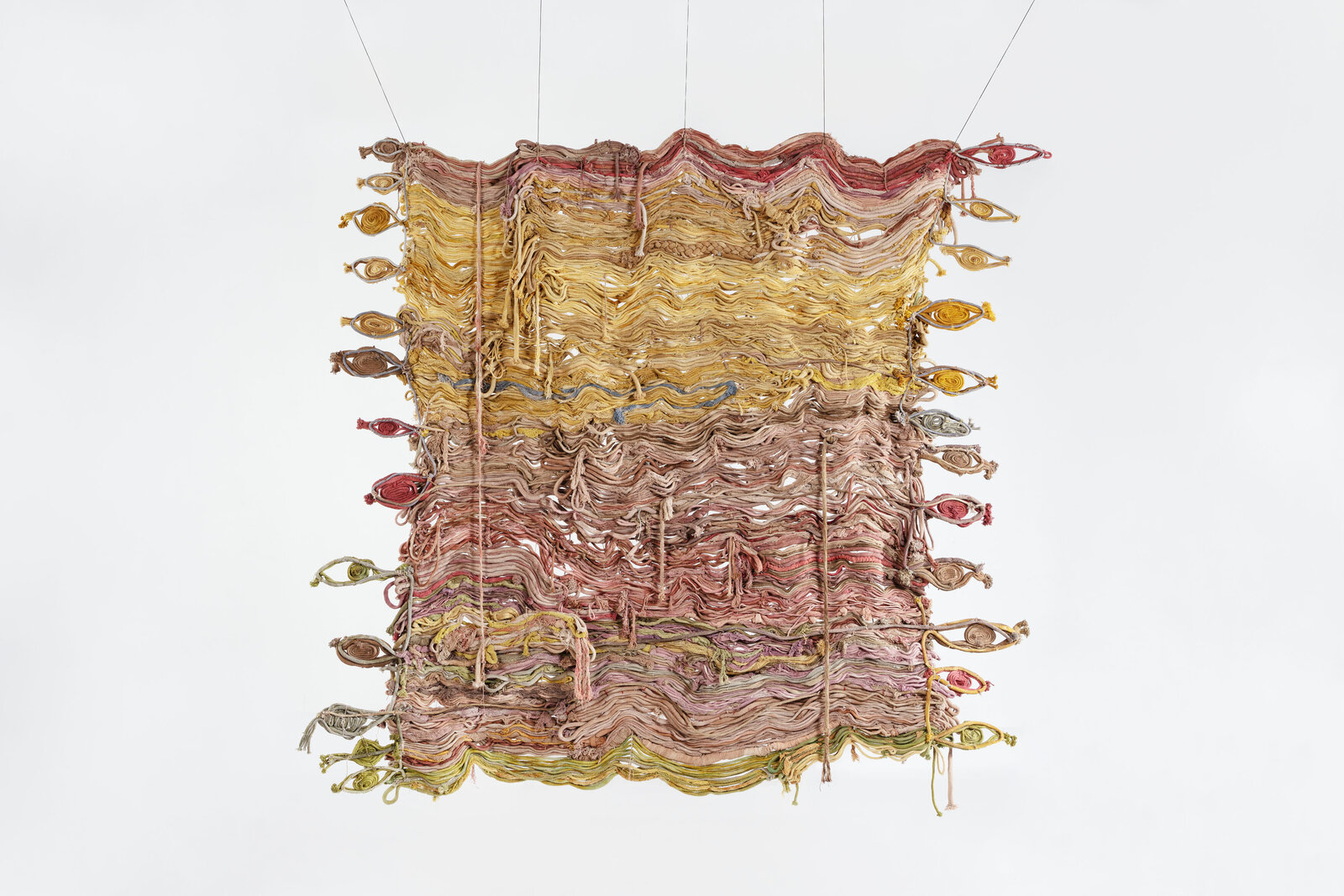 A textured textile artwork featuring layered, wavy threads in earthy tones.