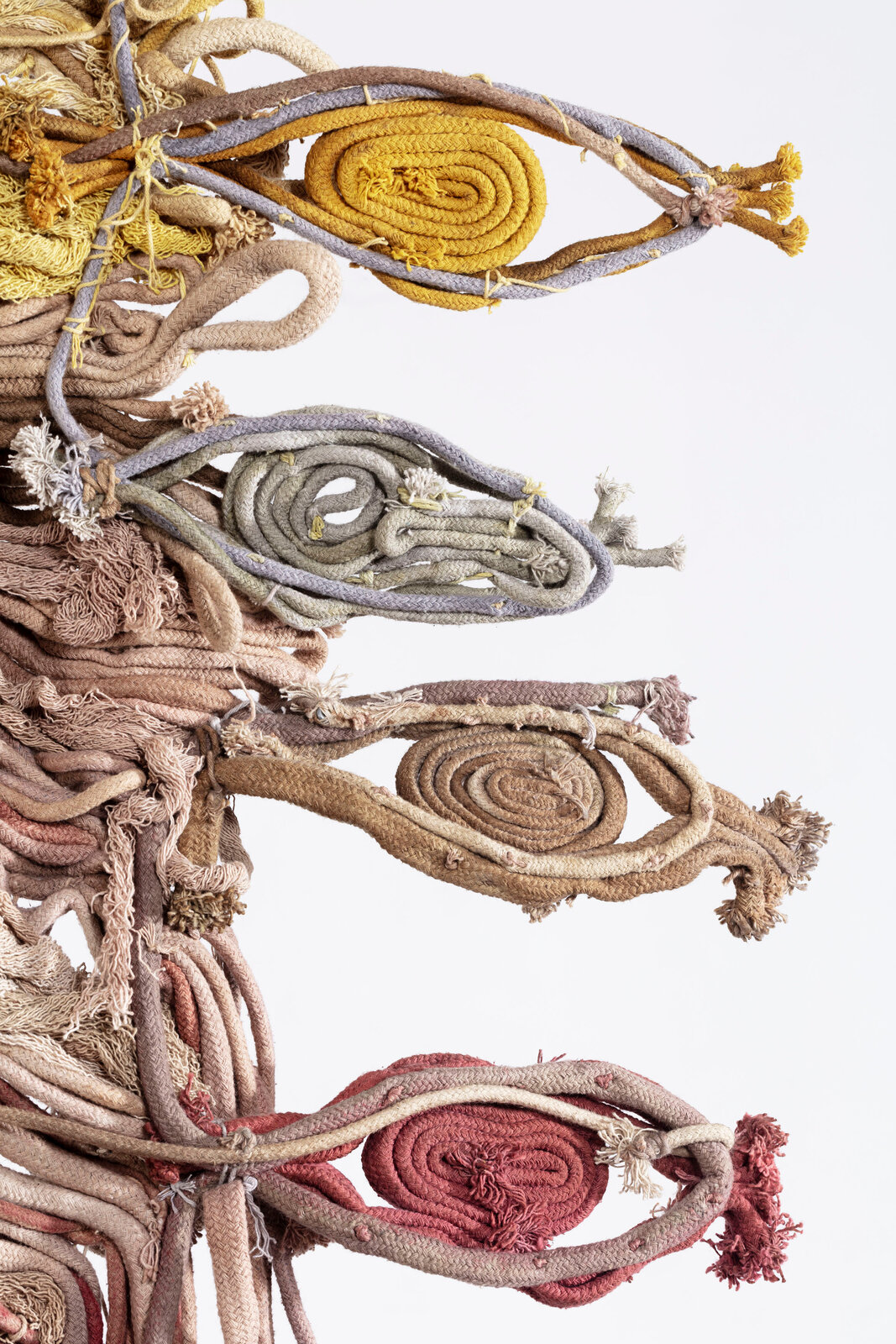 A textured textile artwork featuring layered, wavy threads in earthy tones.