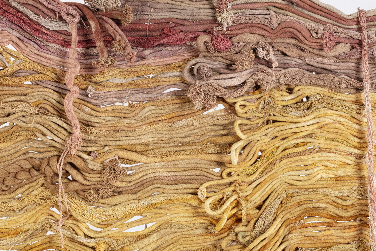A textured textile artwork featuring layered, wavy threads in earthy tones.