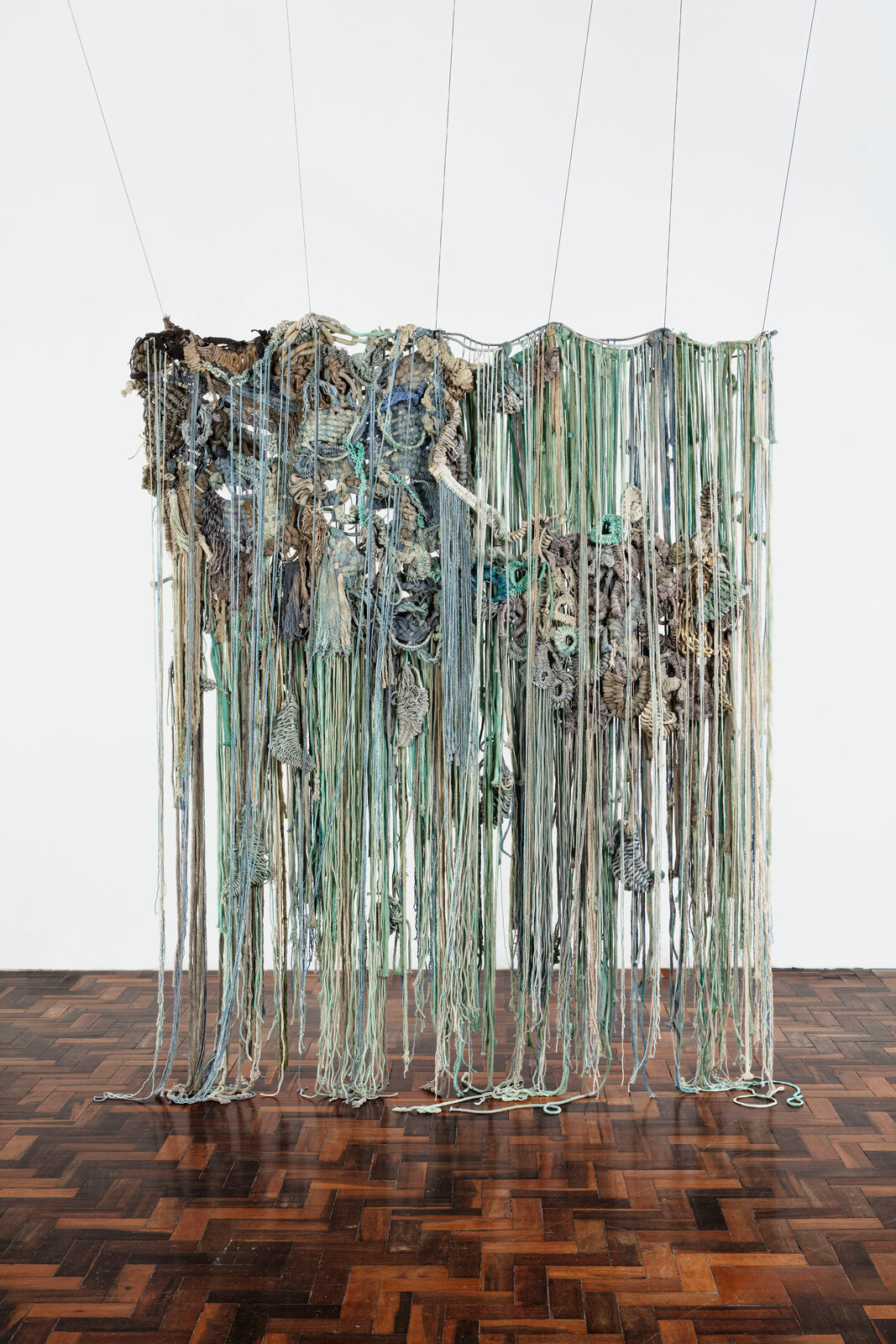 A large piece of art hanging on a wooden floor.