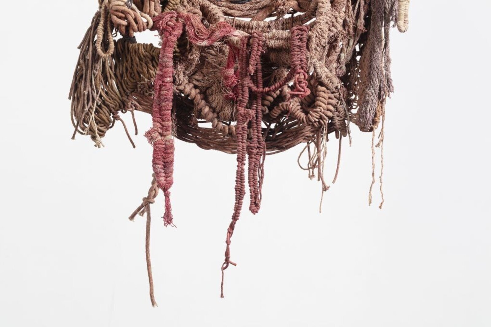 A hanging textile sculpture made of woven fibers and knots.