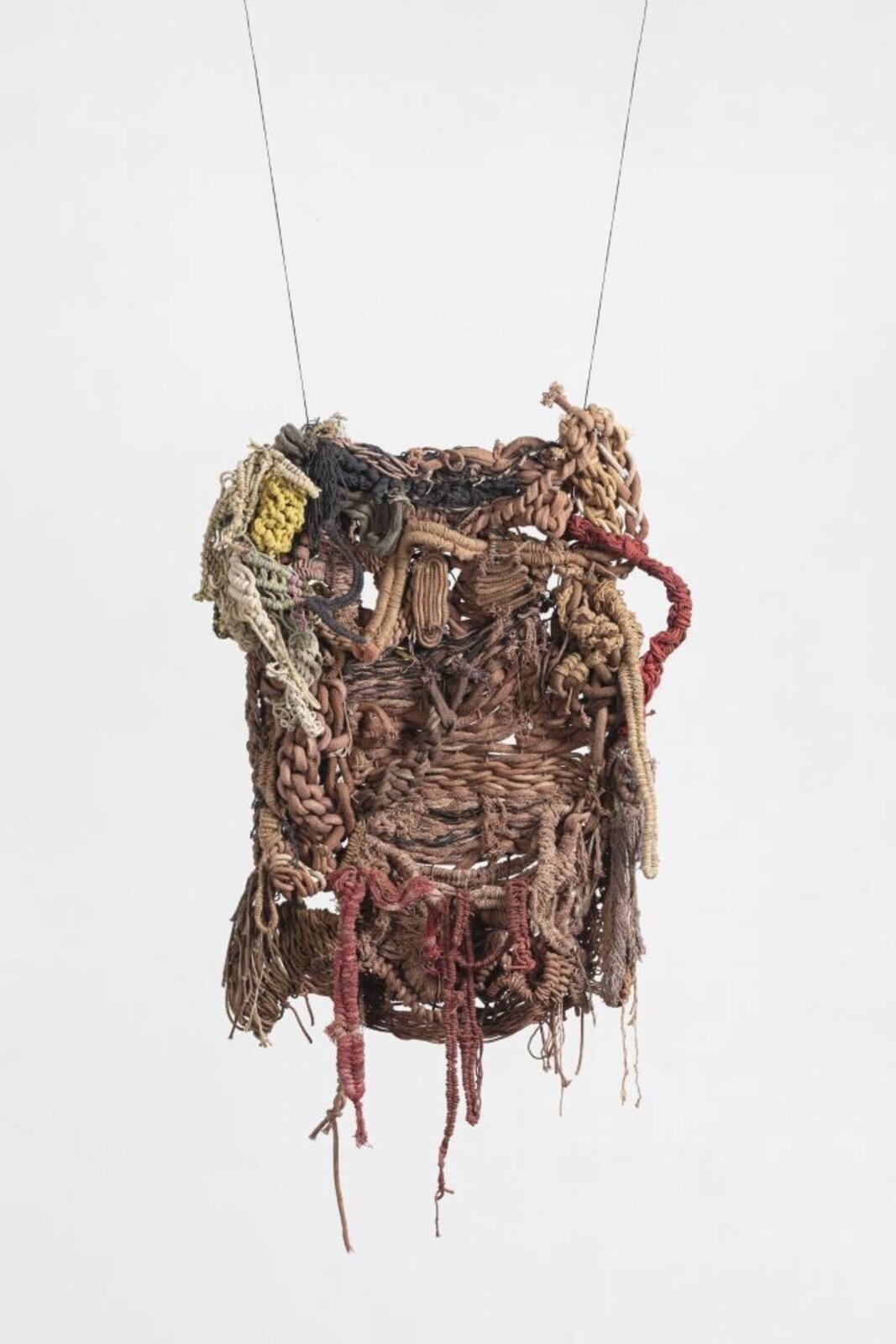 A hanging textile sculpture made of woven fibers and knots.